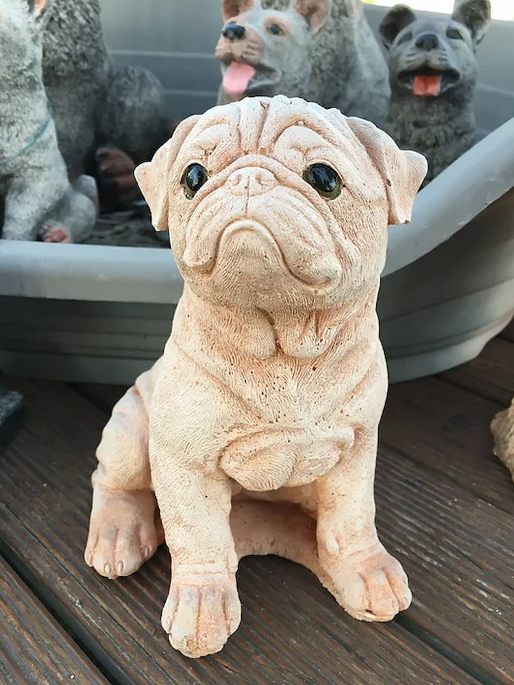 A Statue of a Pug Dog is Sitting on a Wooden Table — Blue River Landscape Supplies in Foulden, QLD
