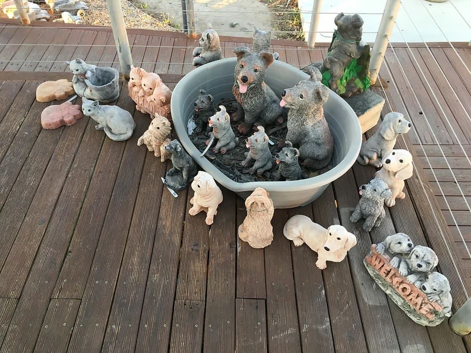 A Bunch of Statues Are Sitting on a Wooden Deck Including a Welcome Sign — Blue River Landscape Supplies in Foulden, QLD