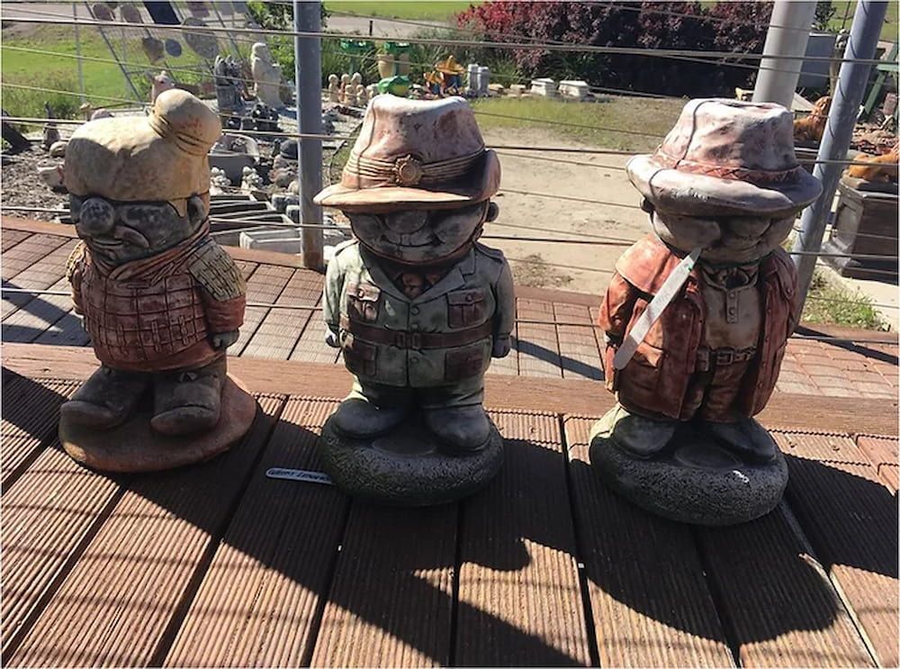 Three Statues of Gnomes Are Sitting on a Wooden Deck — Blue River Landscape Supplies in Foulden, QLD