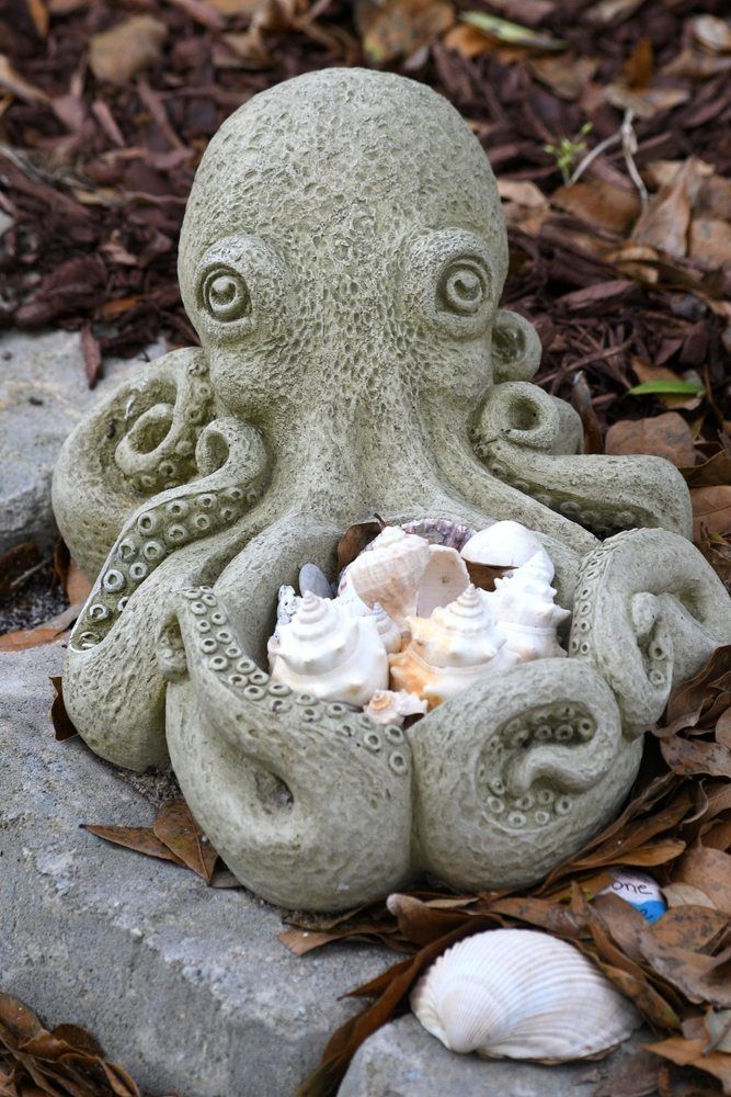 A Statue of an Octopus Holding Seashells is Sitting on a Rock — Blue River Landscape Supplies in Foulden, QLD