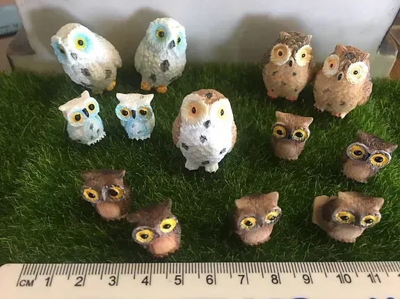 A Group of Owl Figurines Are Sitting on Top of a Green Lawn Next to a Ruler — Blue River Landscape Supplies in Foulden, QLD