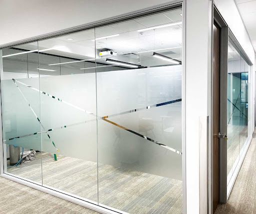 Office space with frosted glass walls and geometric designs.  A door is visible.