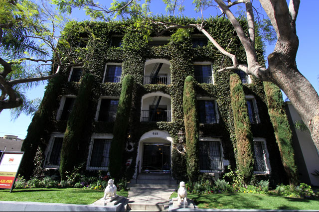 Building facade covered in green ivy, arched entry, windows, and manicured landscaping.