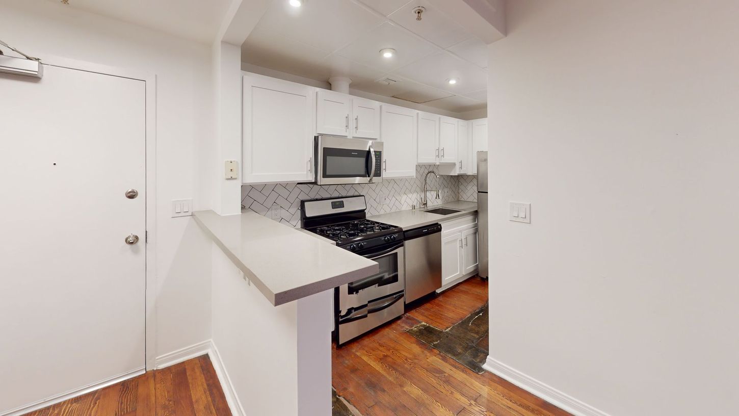 Kitchen with white cabinets, stainless steel appliances, and a breakfast bar.
