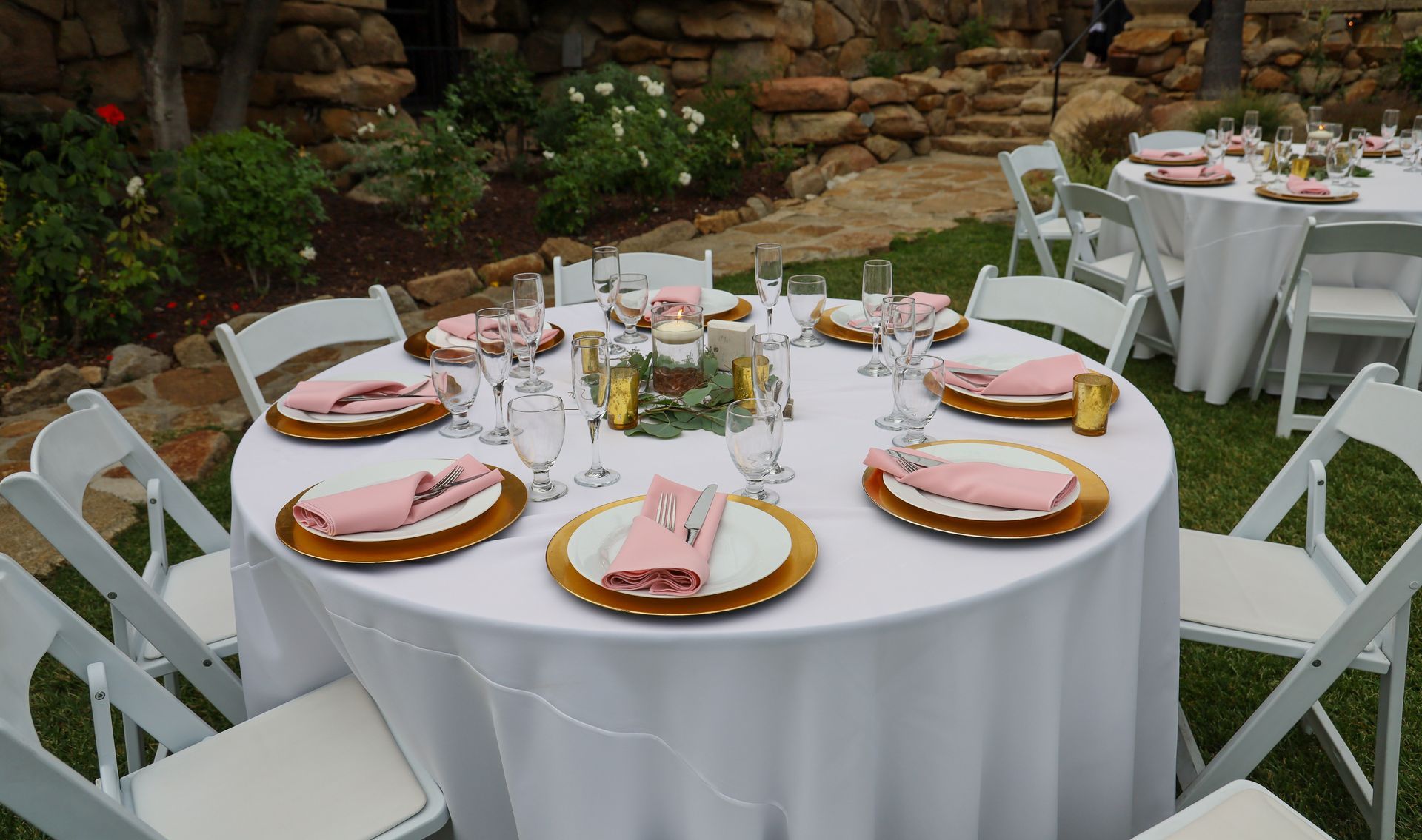 Outdoor wedding setup with round tables, chairs, and linens from event equipment rentals.