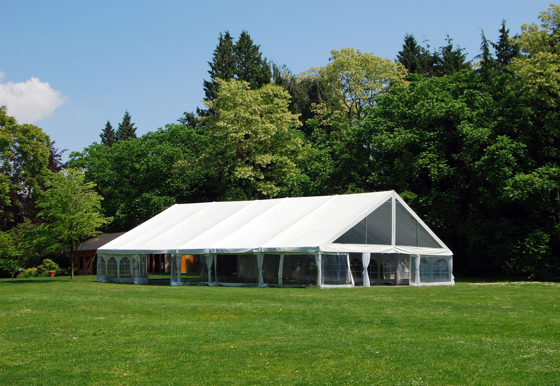 A large tent set up on a lawn for a summer wedding.