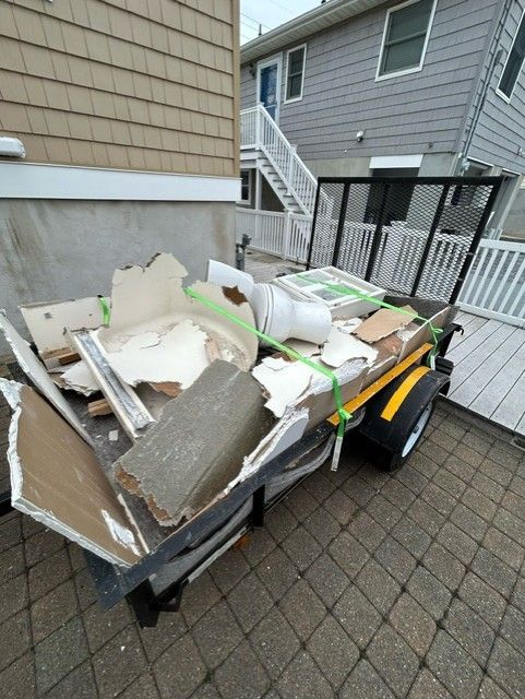 A trailer filled with junk is parked in front of a house.