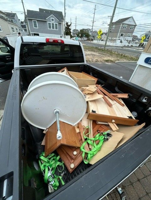 The back of a truck is full of junk and a satellite dish