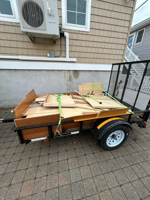 A trailer filled with cardboard boxes is parked in front of a house.