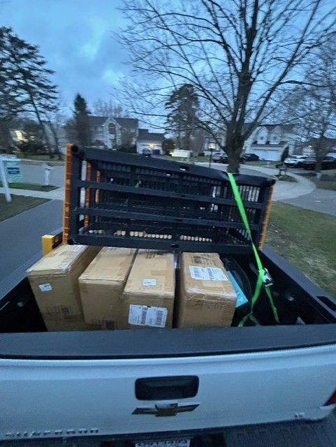 A white truck with boxes in the back is parked in a driveway.
