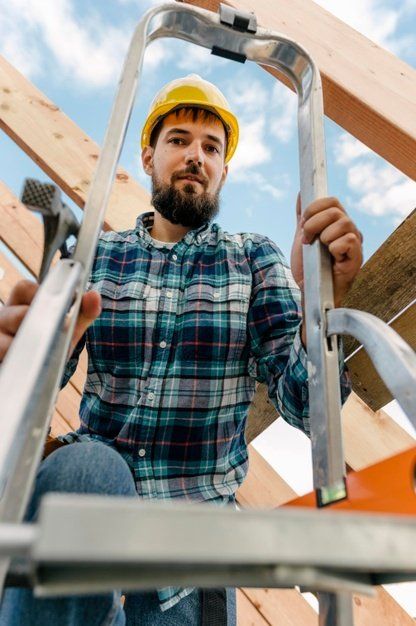 A man is sitting on a ladder at a construction site.