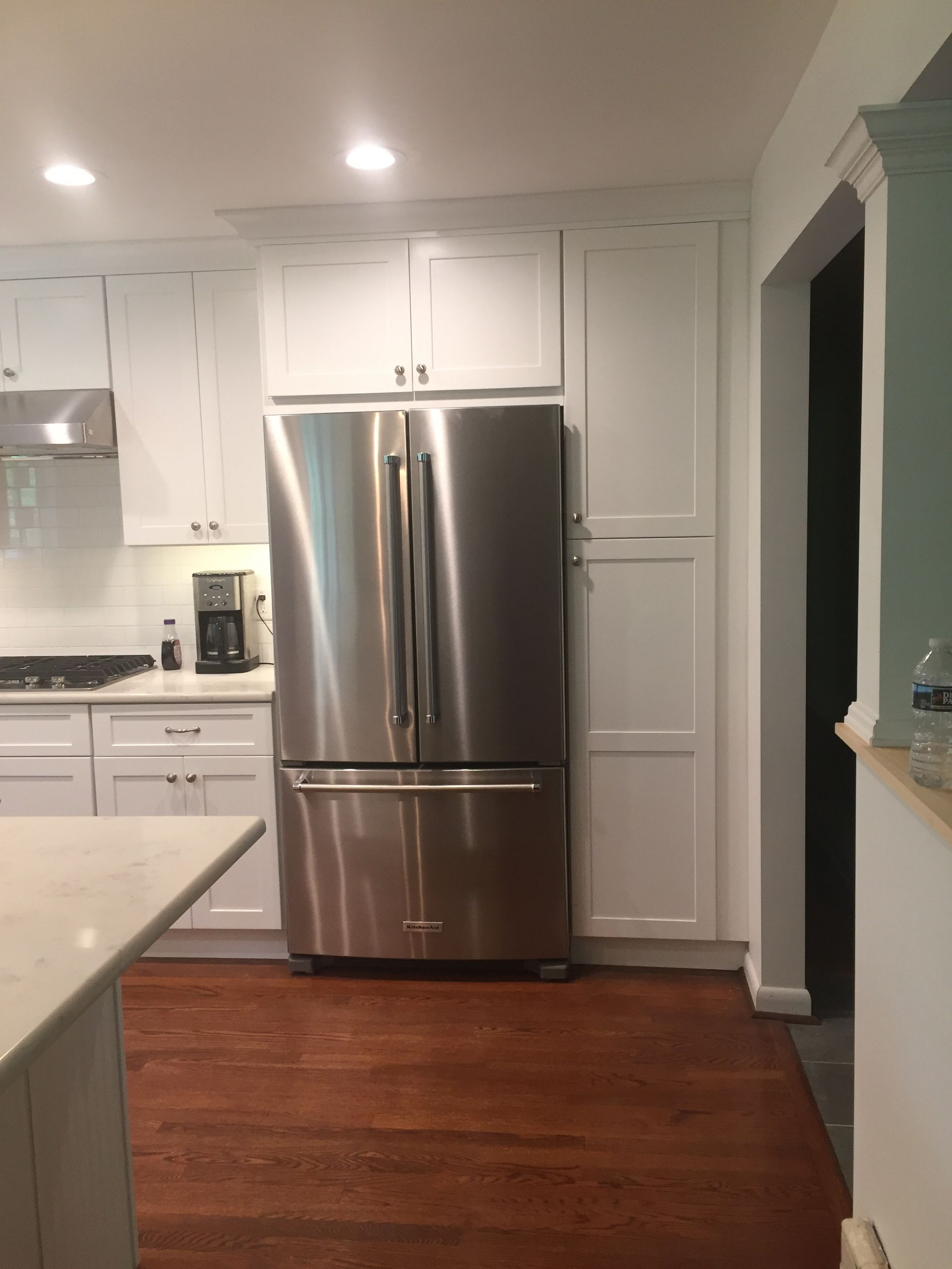 A kitchen with white cabinets and a stainless steel refrigerator