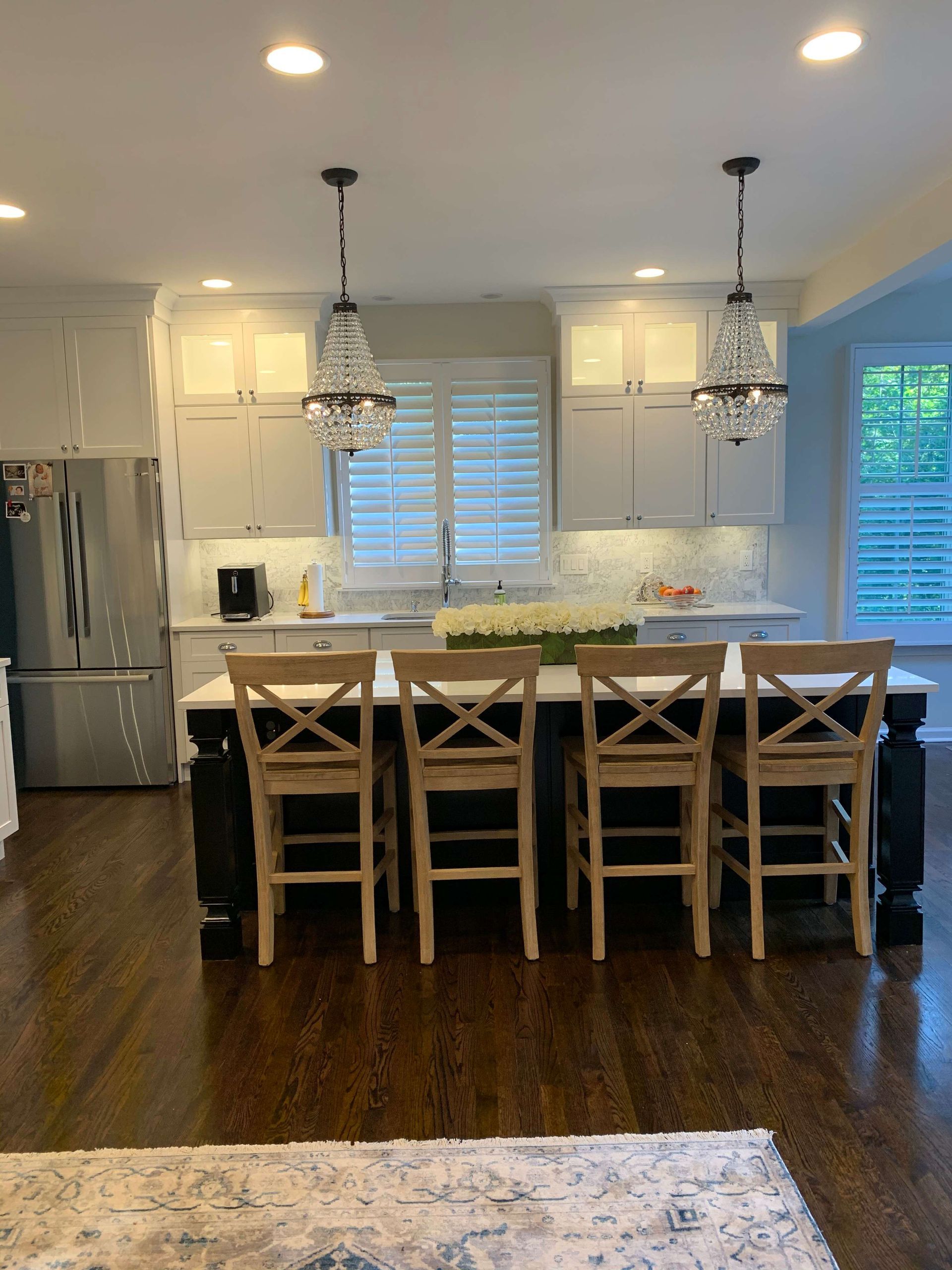 A kitchen with white cabinets and wooden chairs
