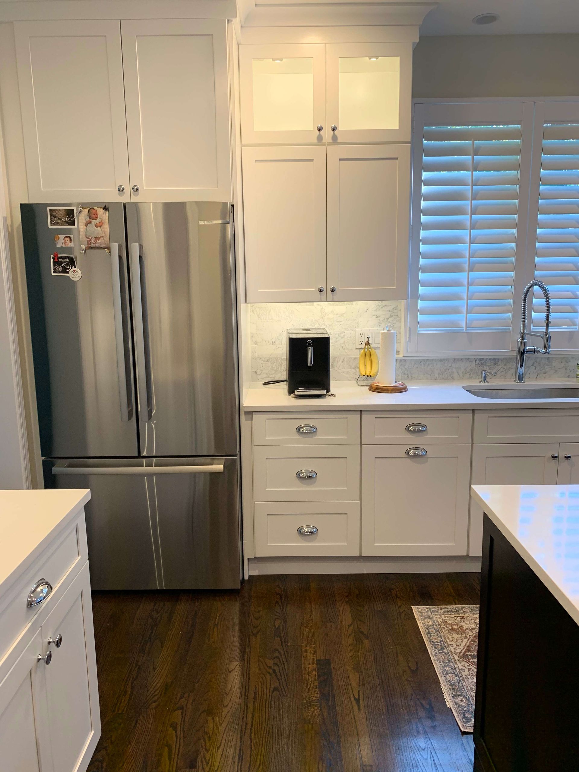 A kitchen with white cabinets and a stainless steel refrigerator.