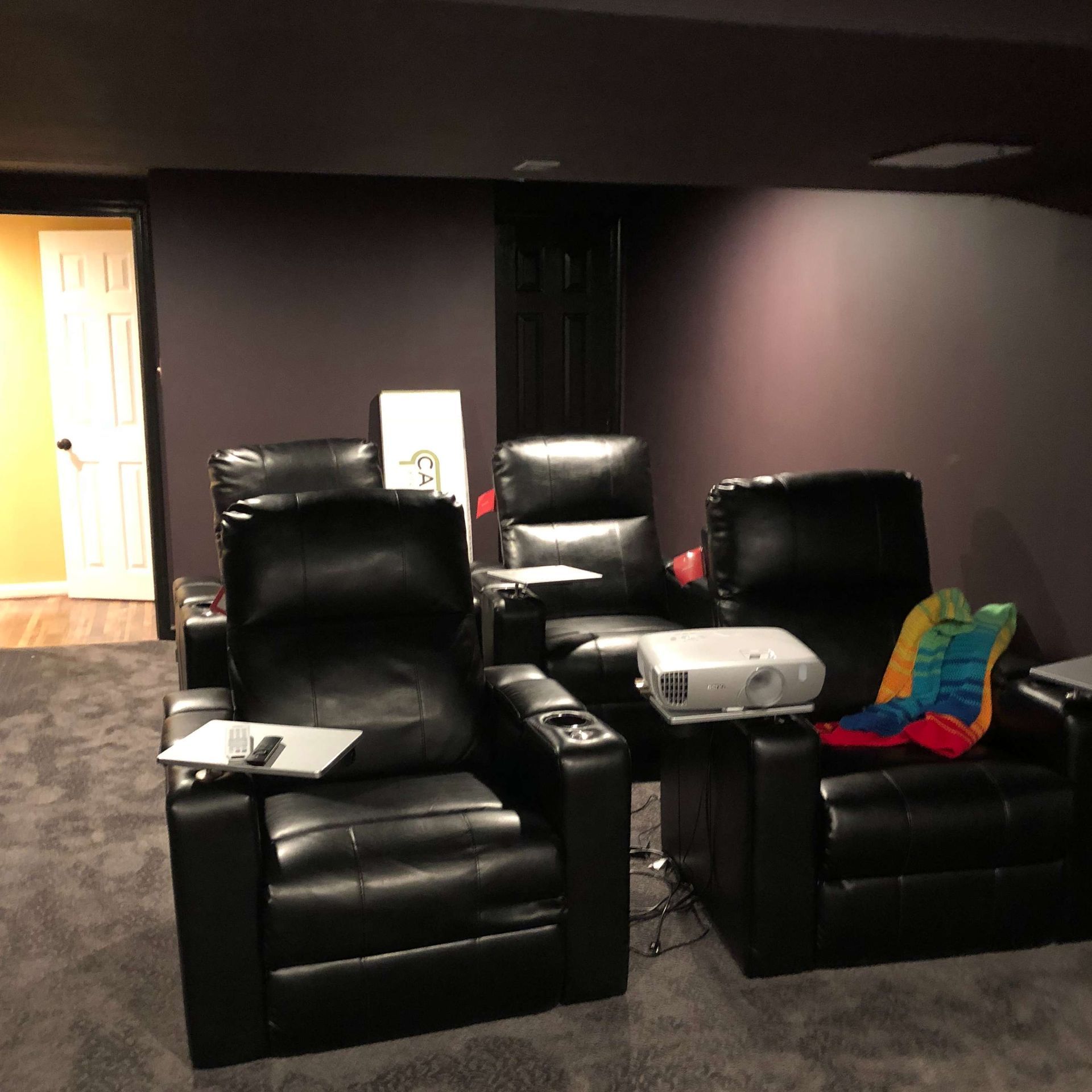 A home theater with two black leather chairs and a projector