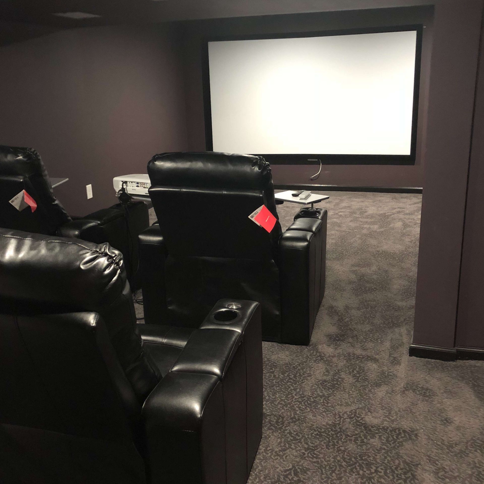 A home theater with black leather chairs and a large screen