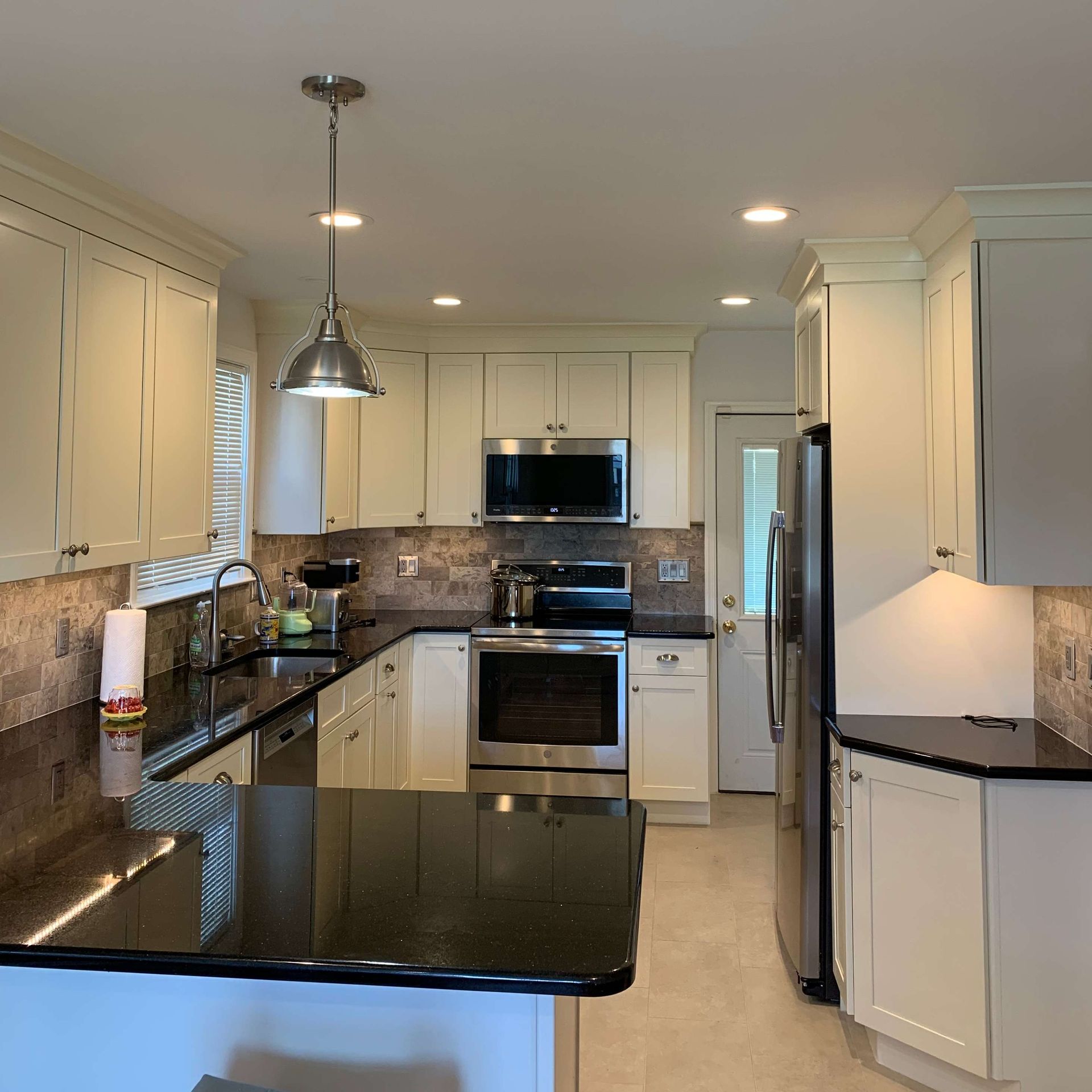A kitchen with white cabinets and black counter tops