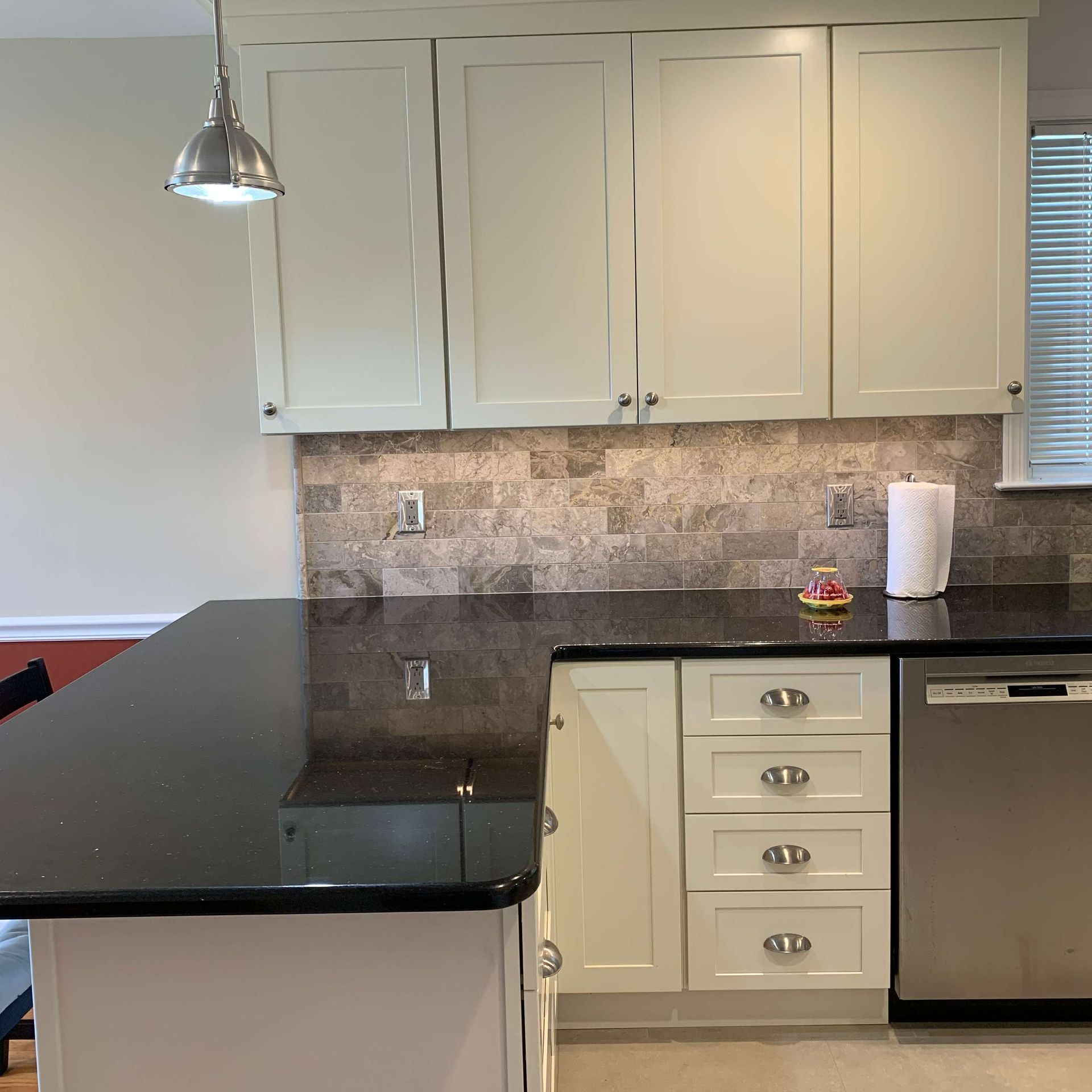 A kitchen with white cabinets and a black counter top
