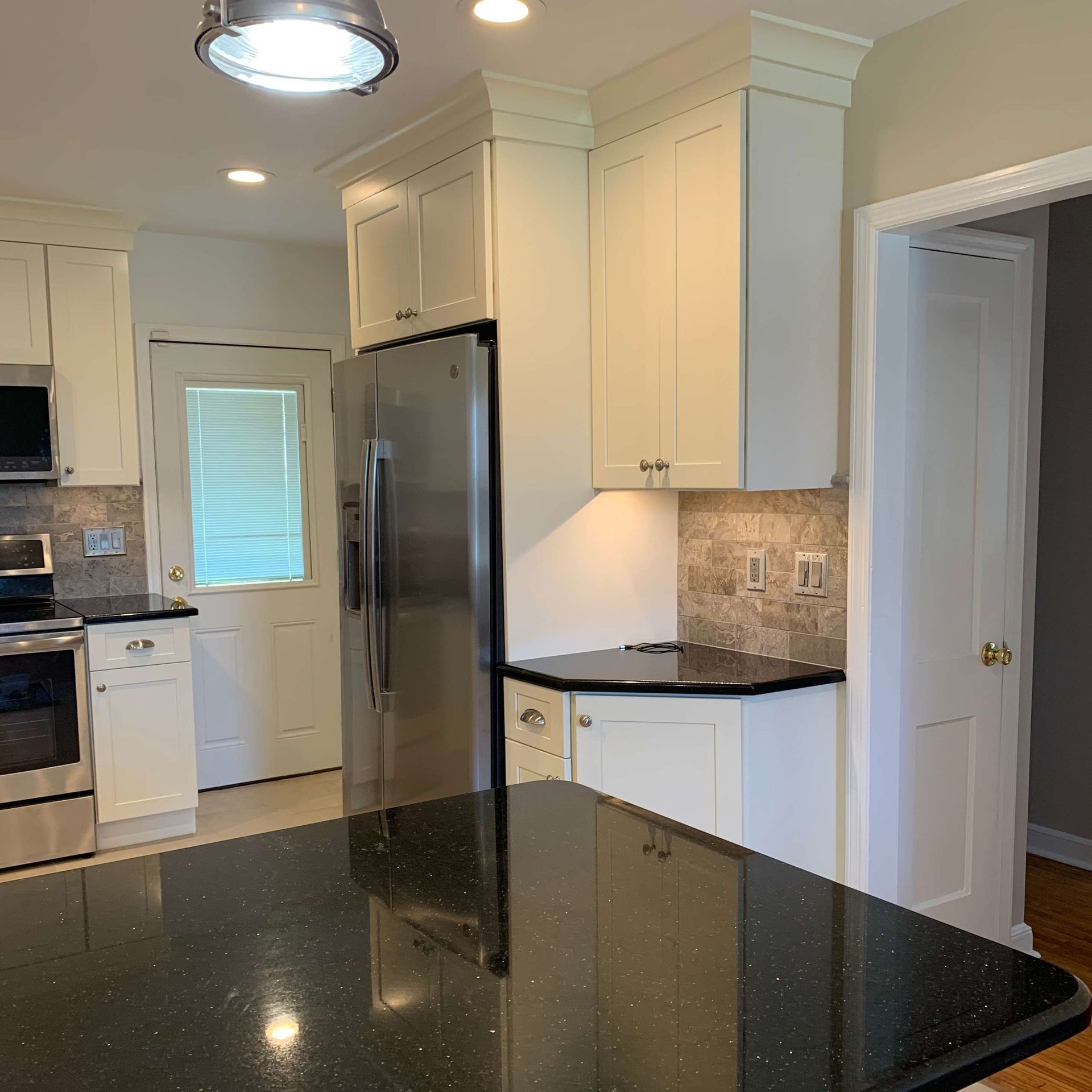 A kitchen with white cabinets and a stainless steel refrigerator