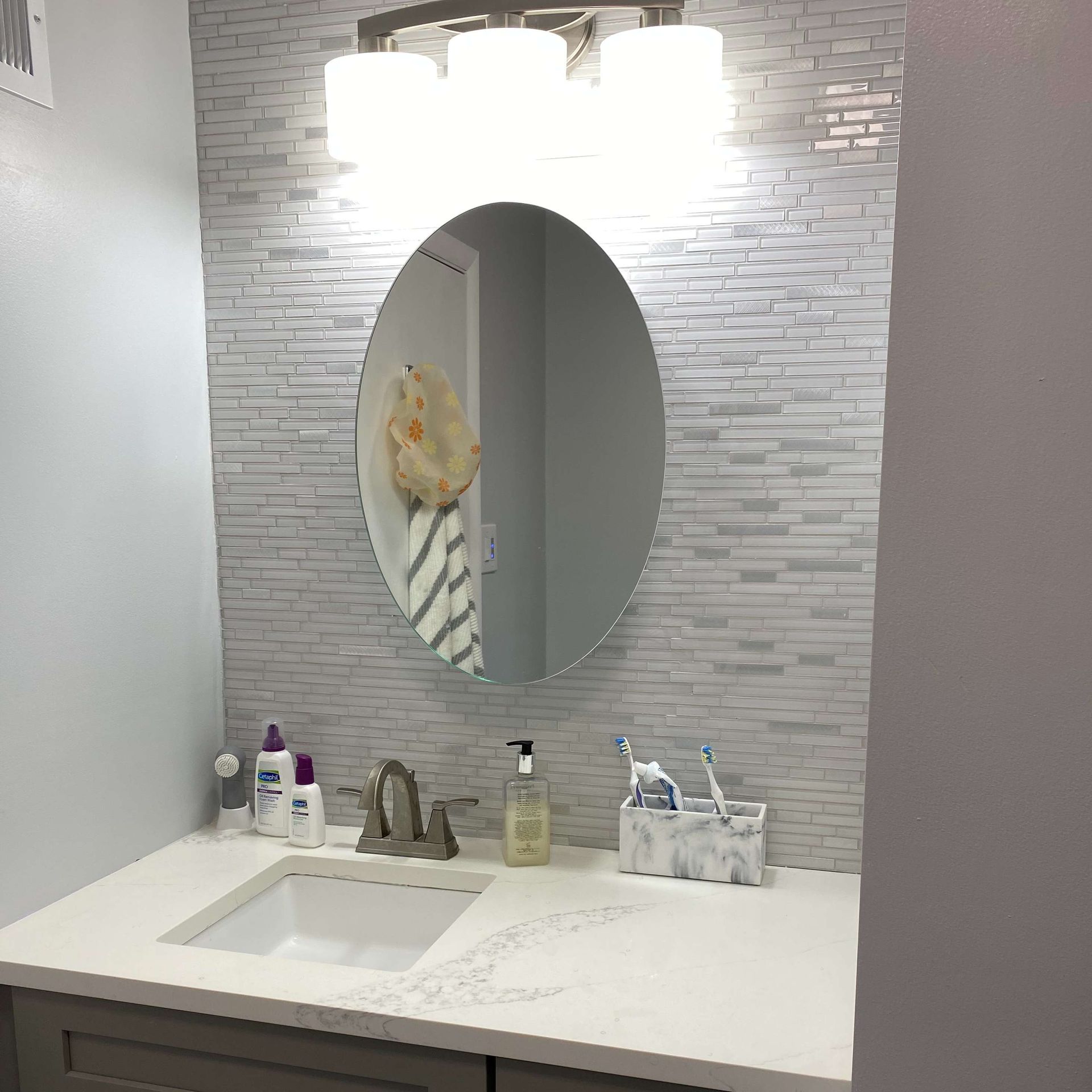 A bathroom with a sink , mirror and light fixture.
