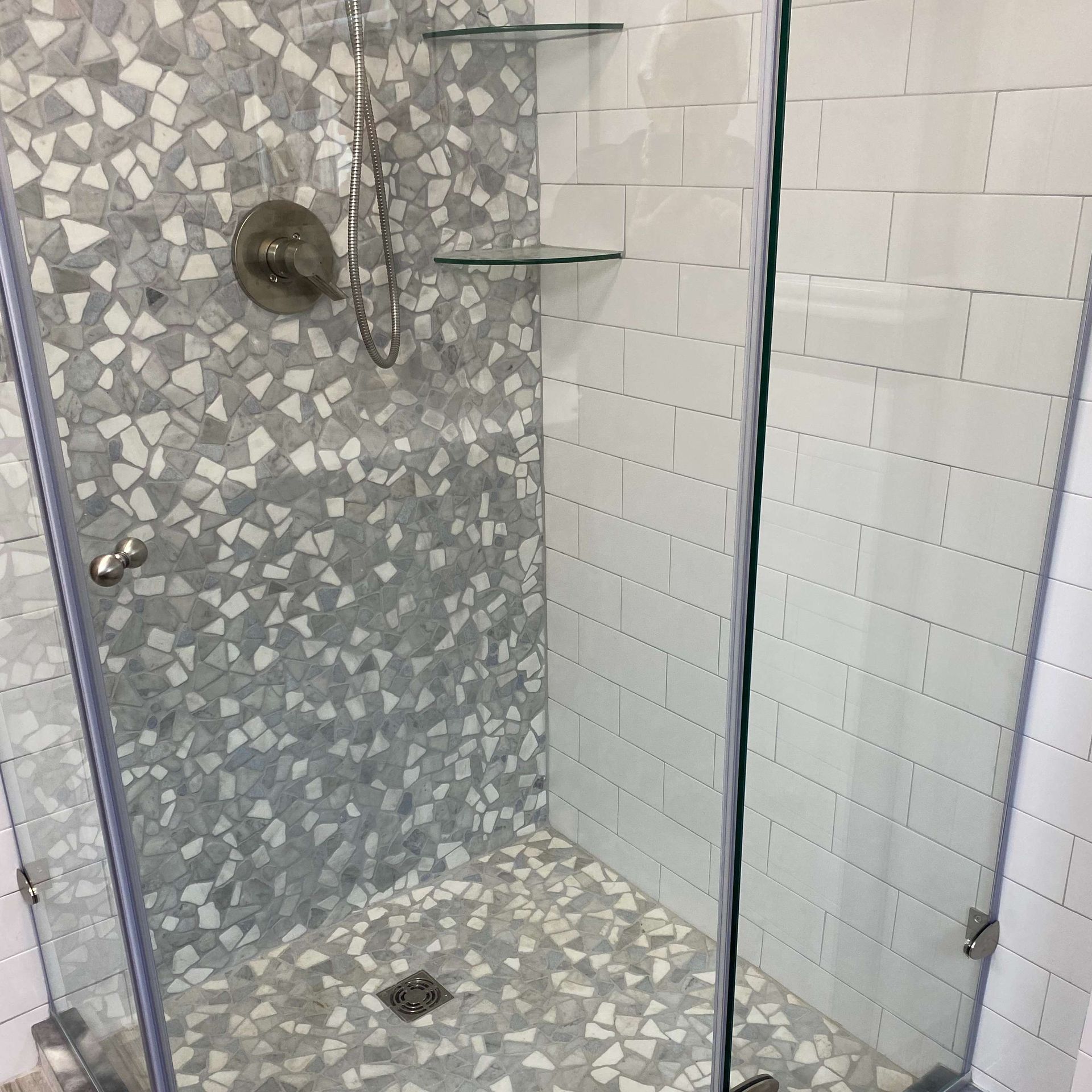 A bathroom with a walk in shower with a glass door