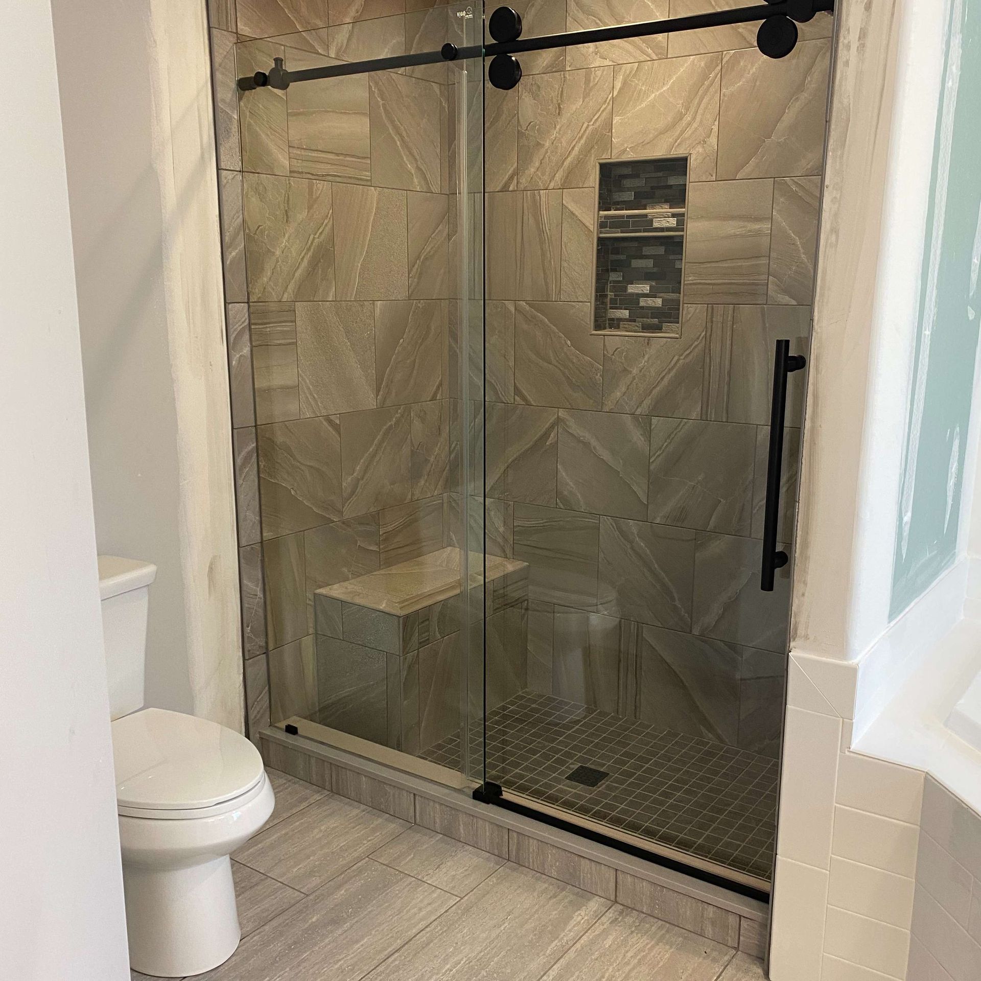 A bathroom with a toilet and a shower with a sliding glass door.