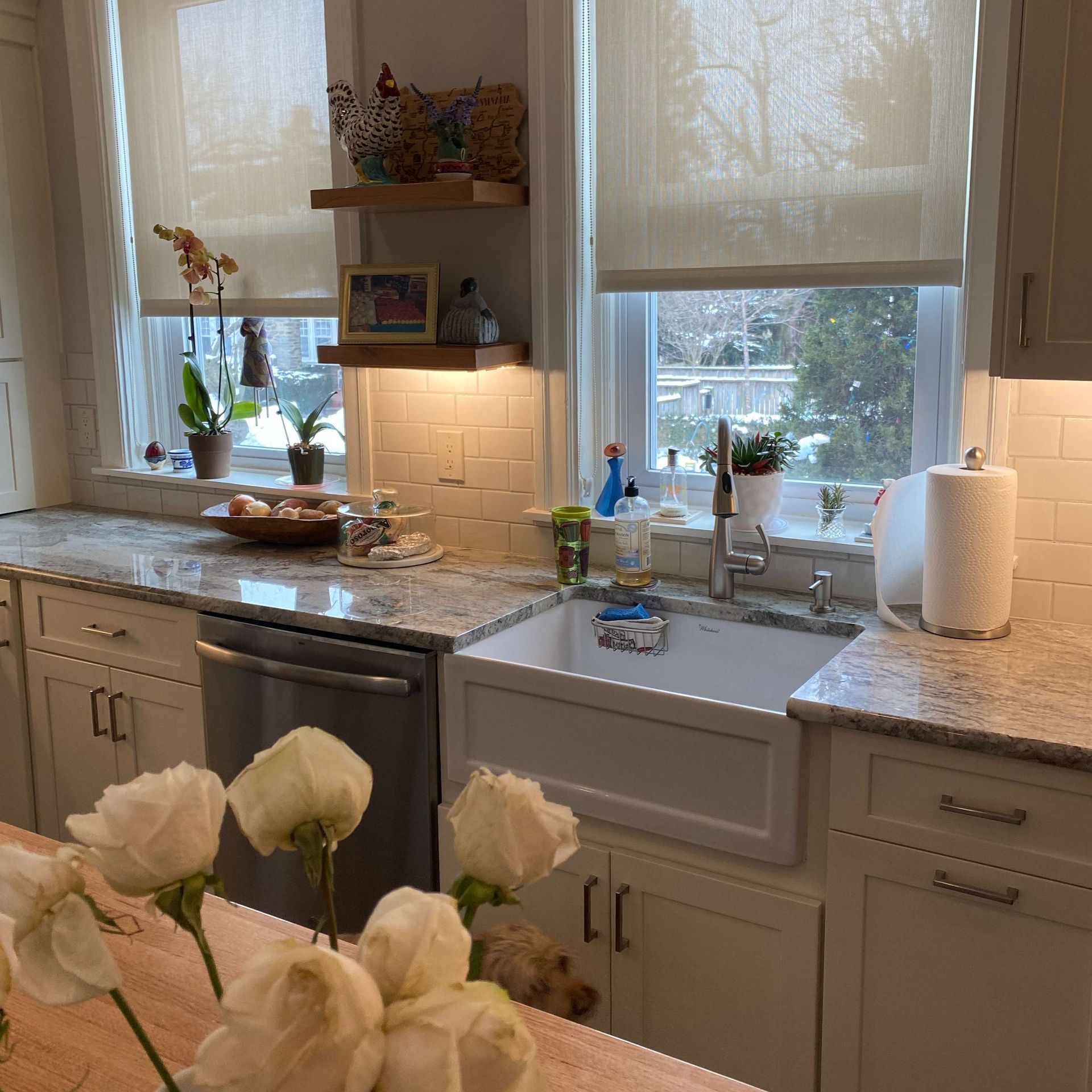 A kitchen with white cabinets a sink and a window