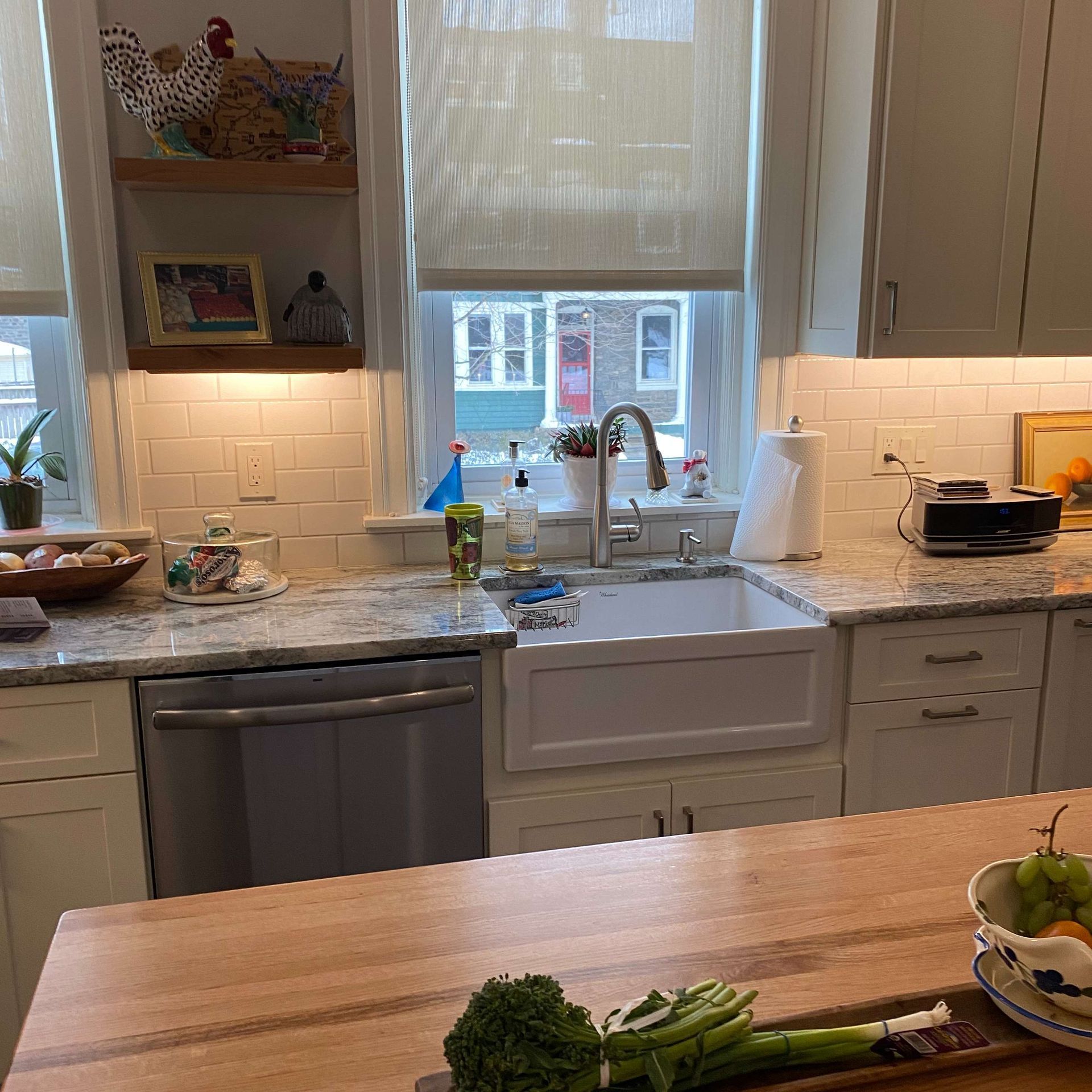 A kitchen with a sink and a bowl of broccoli on the counter.