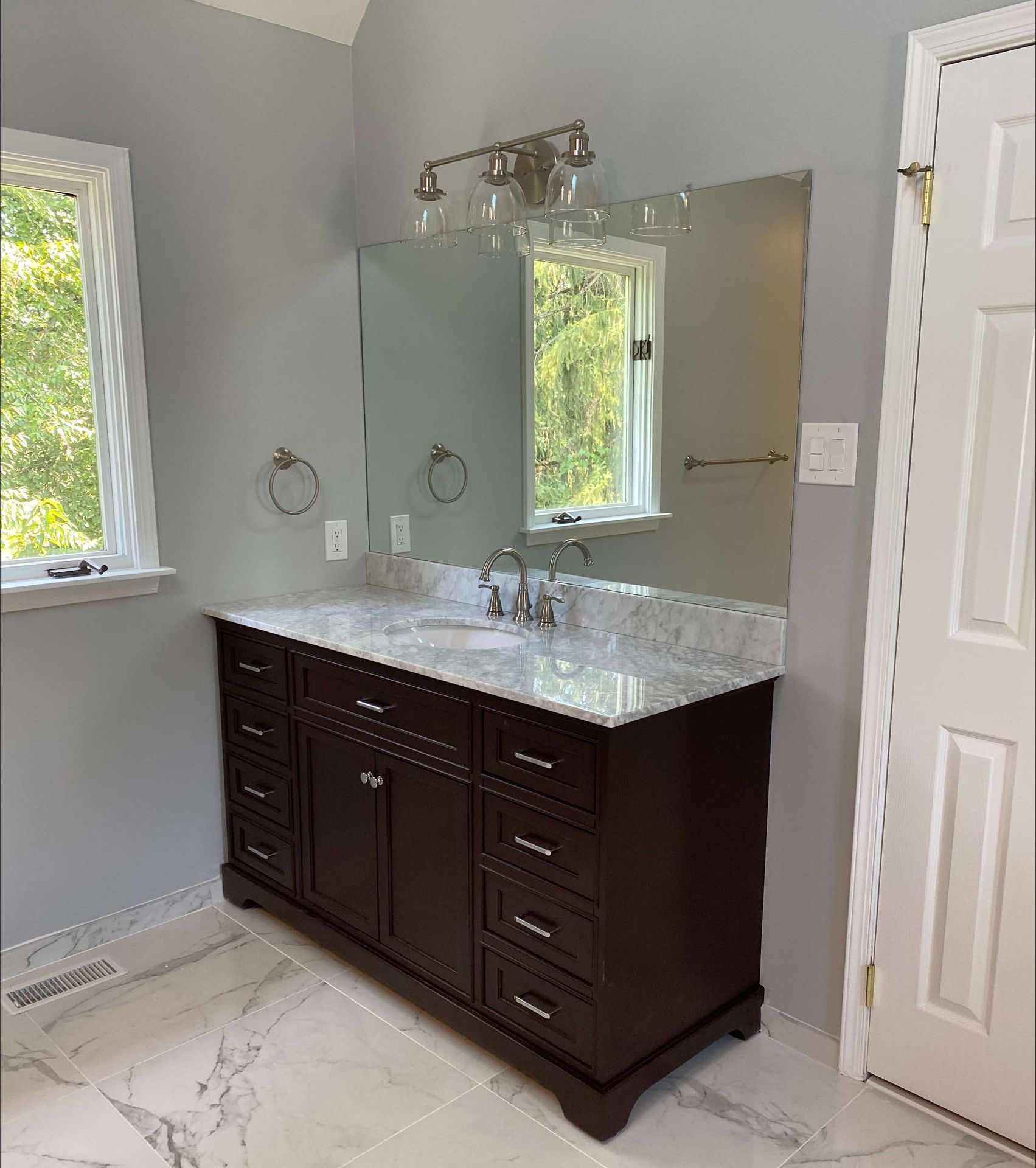 A bathroom with a sink , mirror and window.