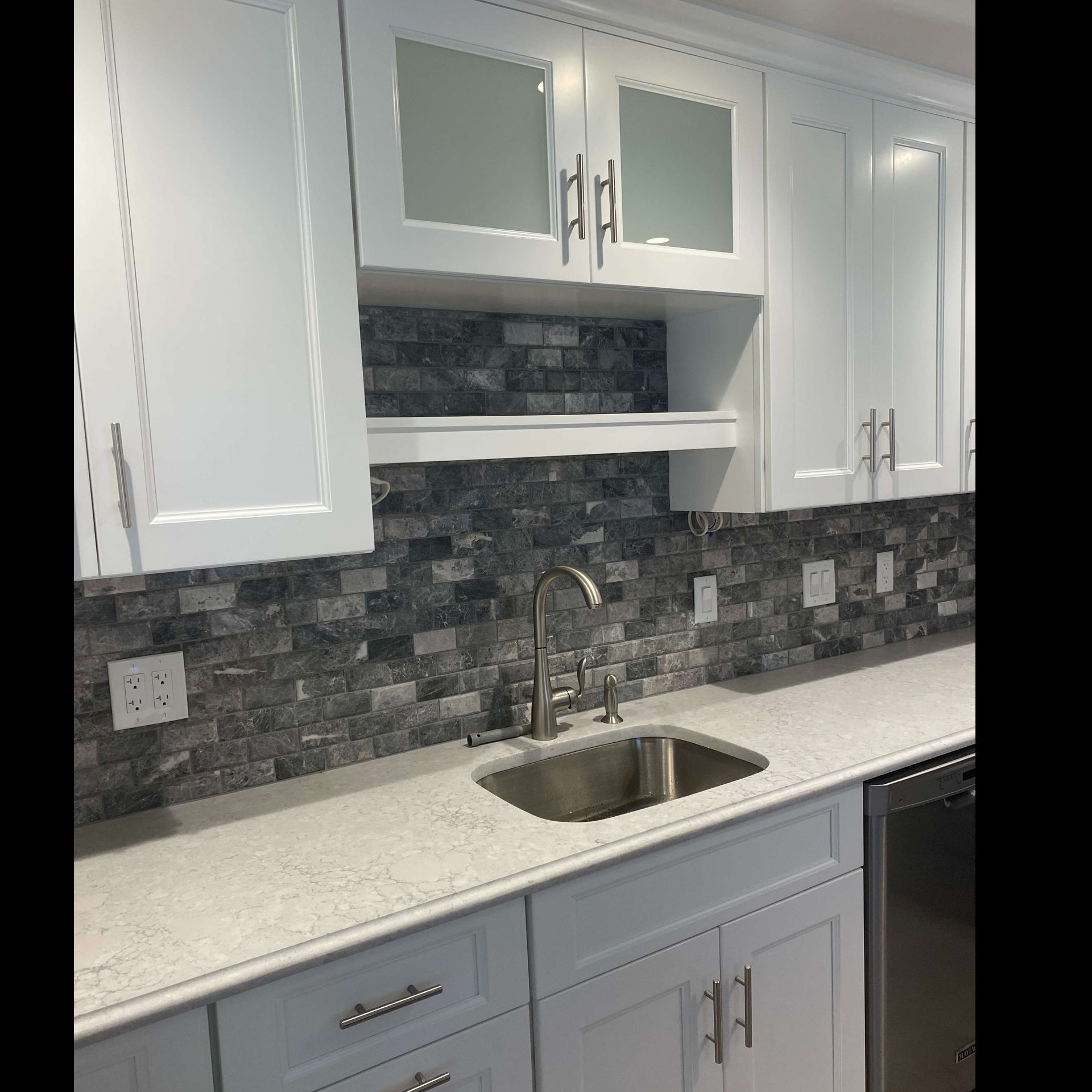 A kitchen with white cabinets and a stainless steel sink