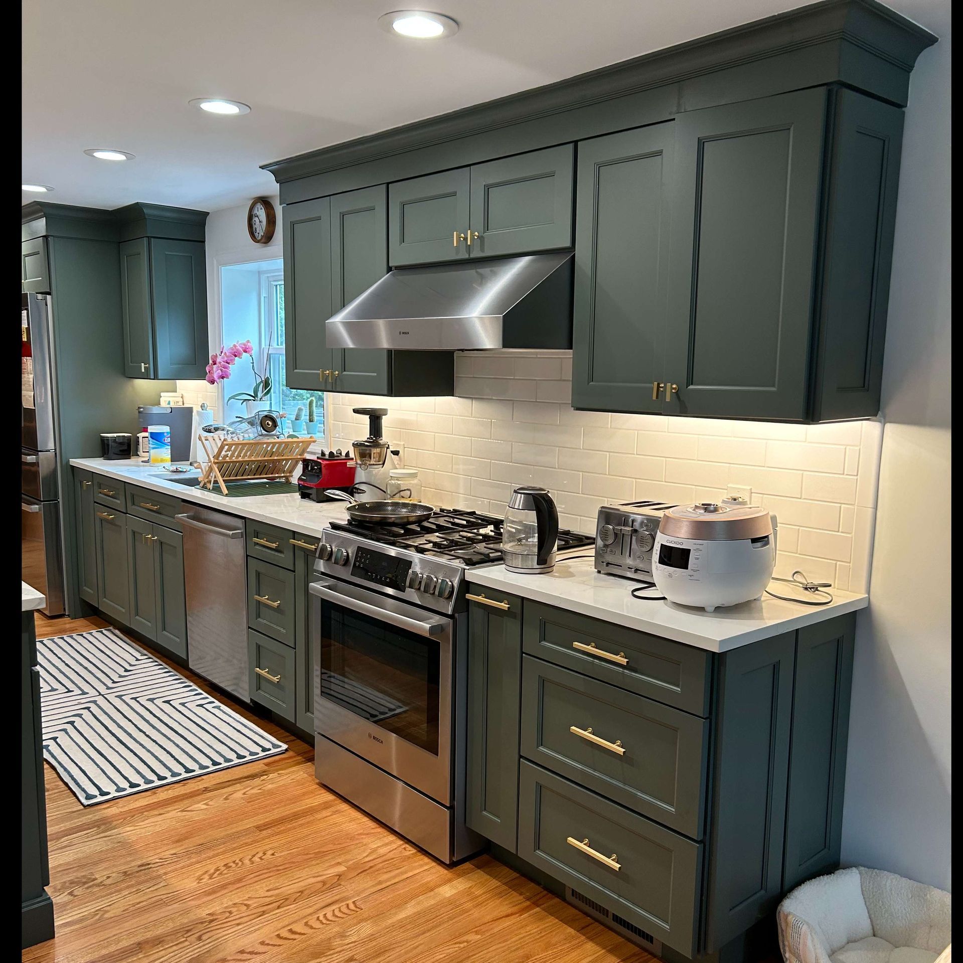 A kitchen with green cabinets and stainless steel appliances