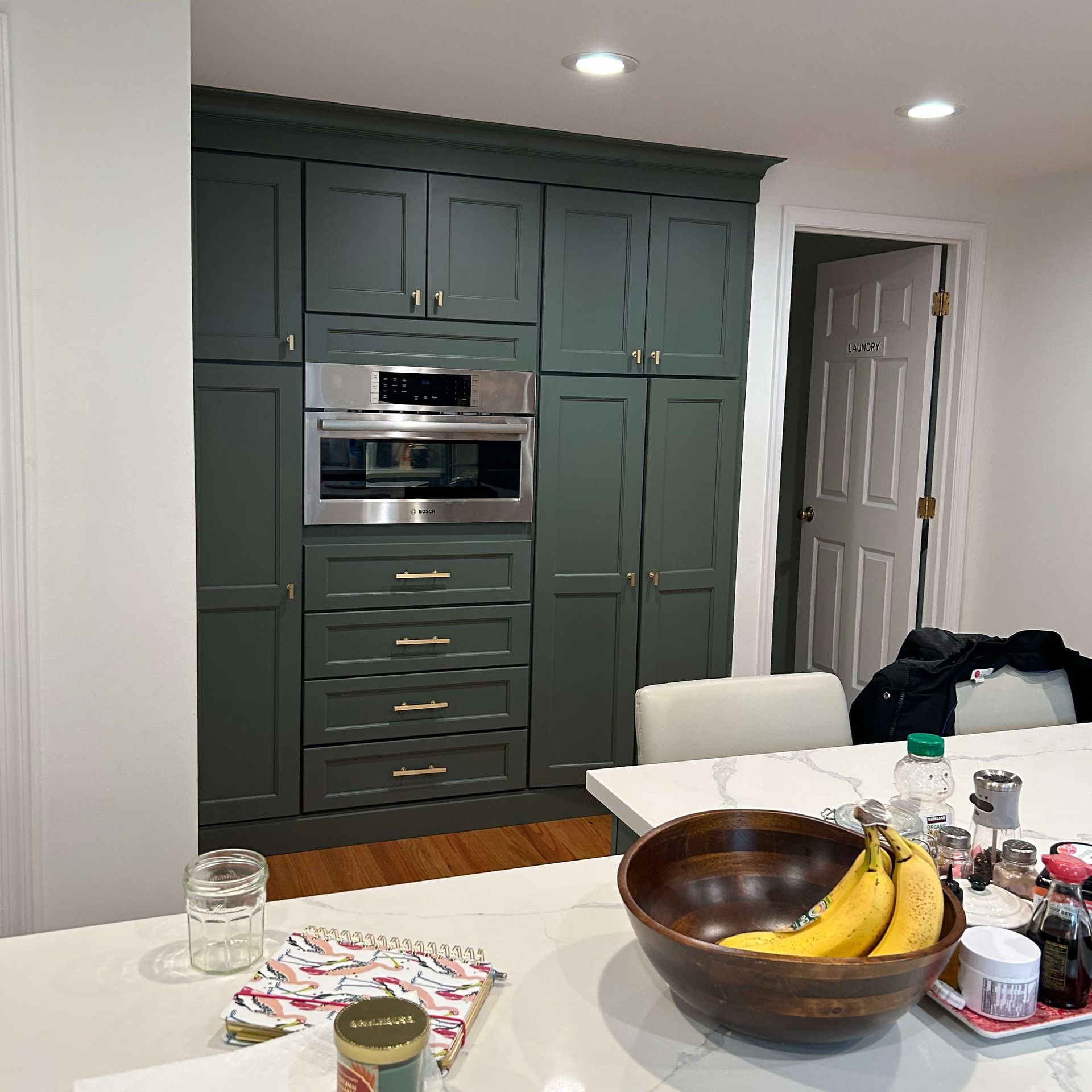 A bowl of bananas sits on a table in a kitchen
