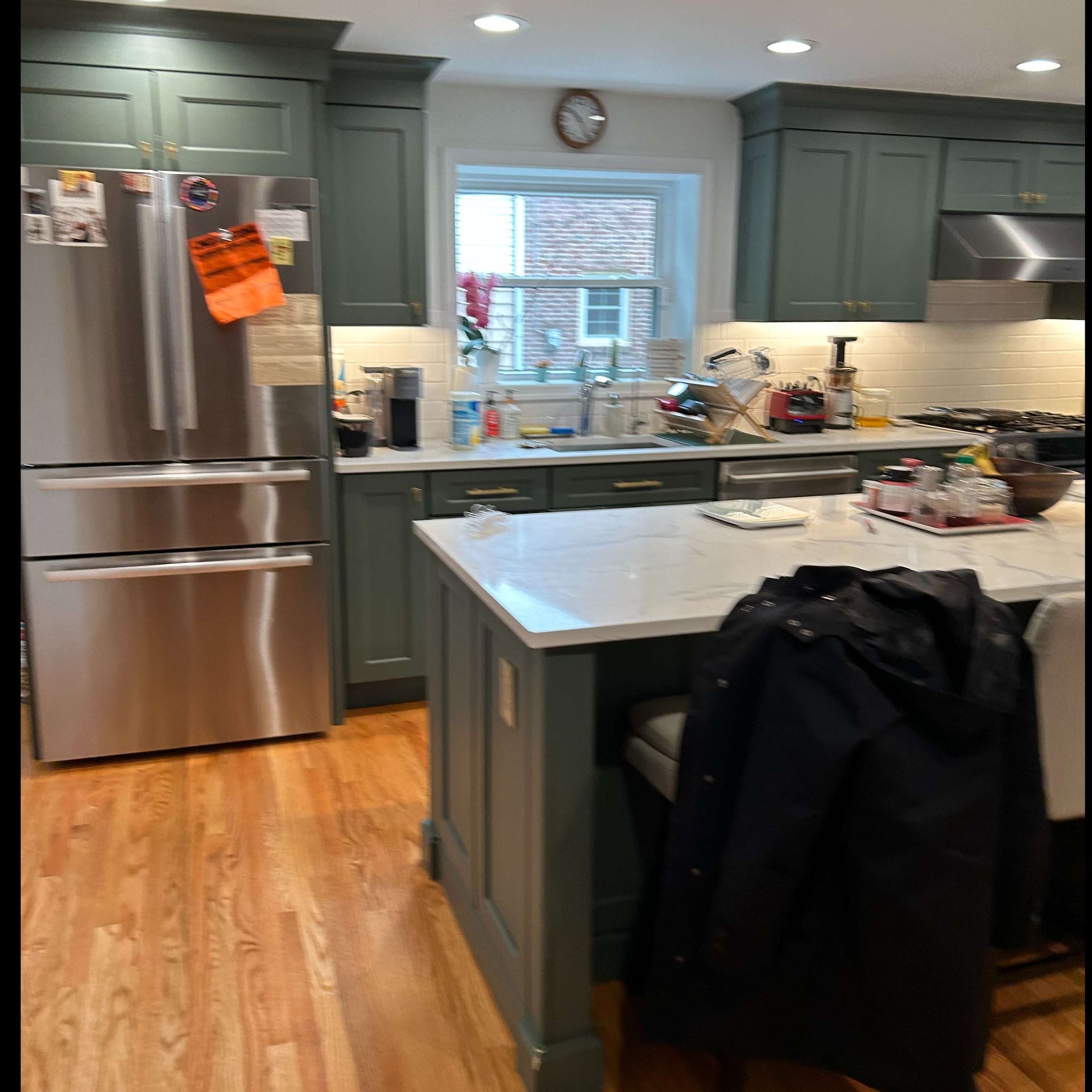 A kitchen with stainless steel appliances and green cabinets