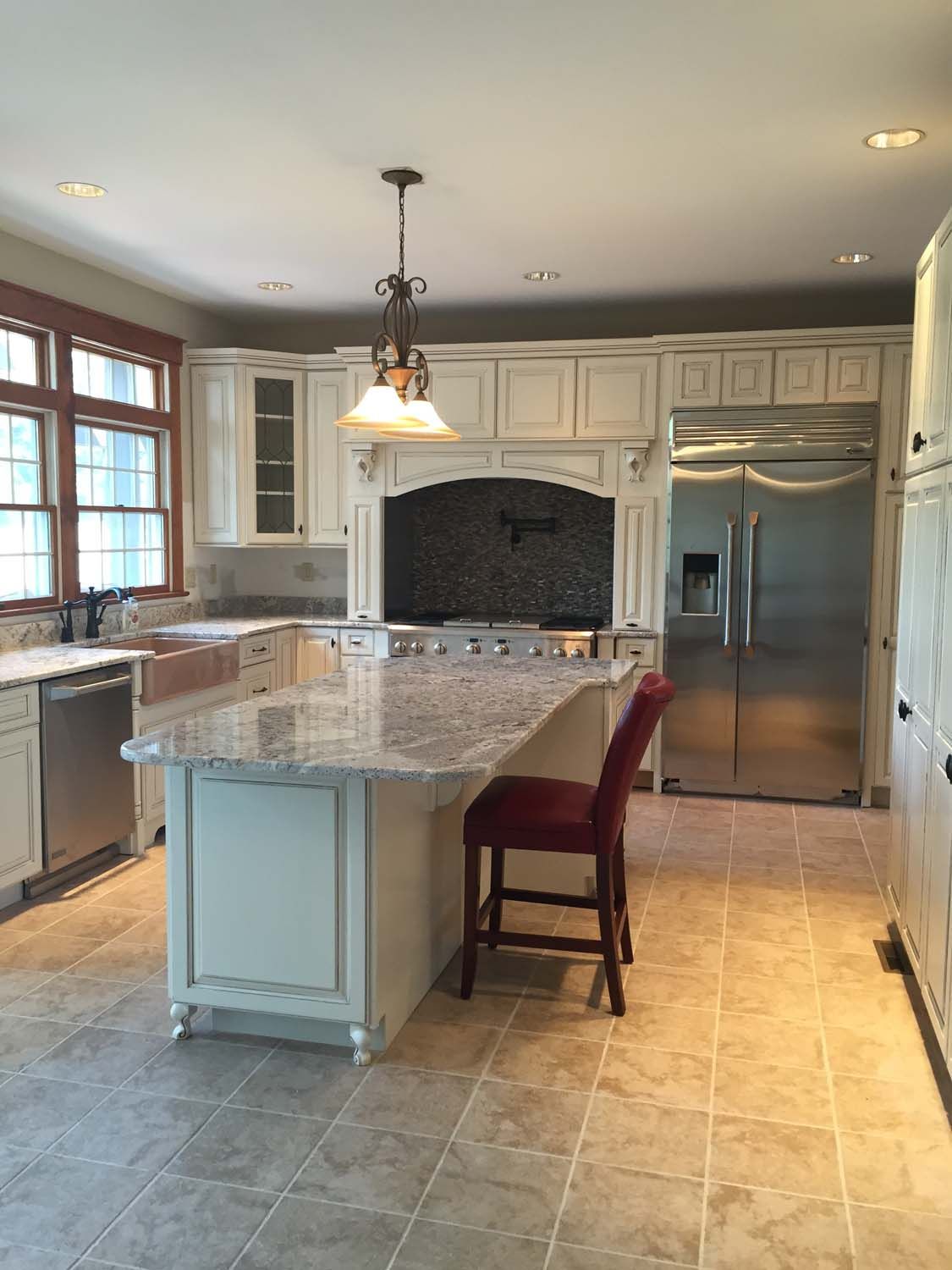 A kitchen with white cabinets , granite counter tops , stainless steel appliances and a large island.