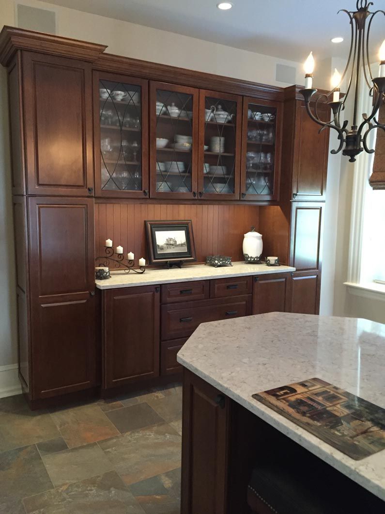 A kitchen with wooden cabinets and a marble counter top