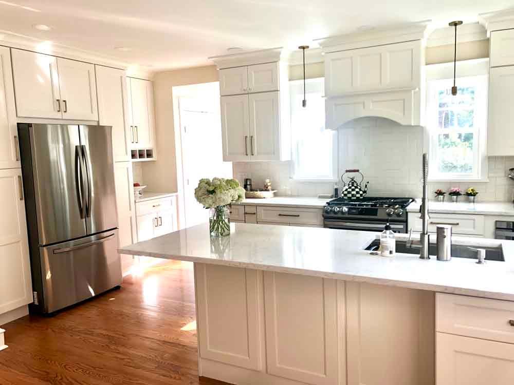 A kitchen with white cabinets , stainless steel appliances , and a large island.