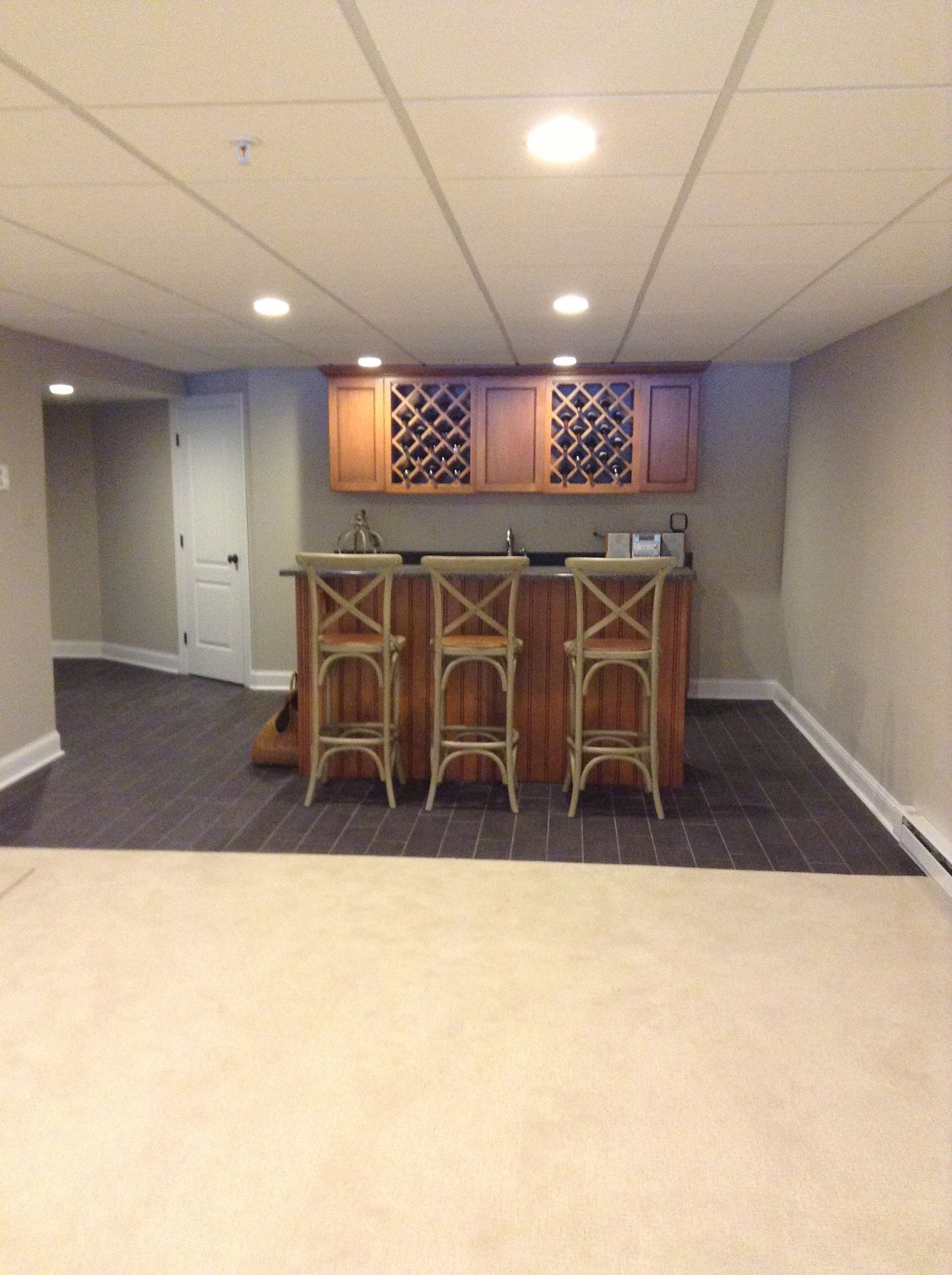 A basement with a bar and three stools