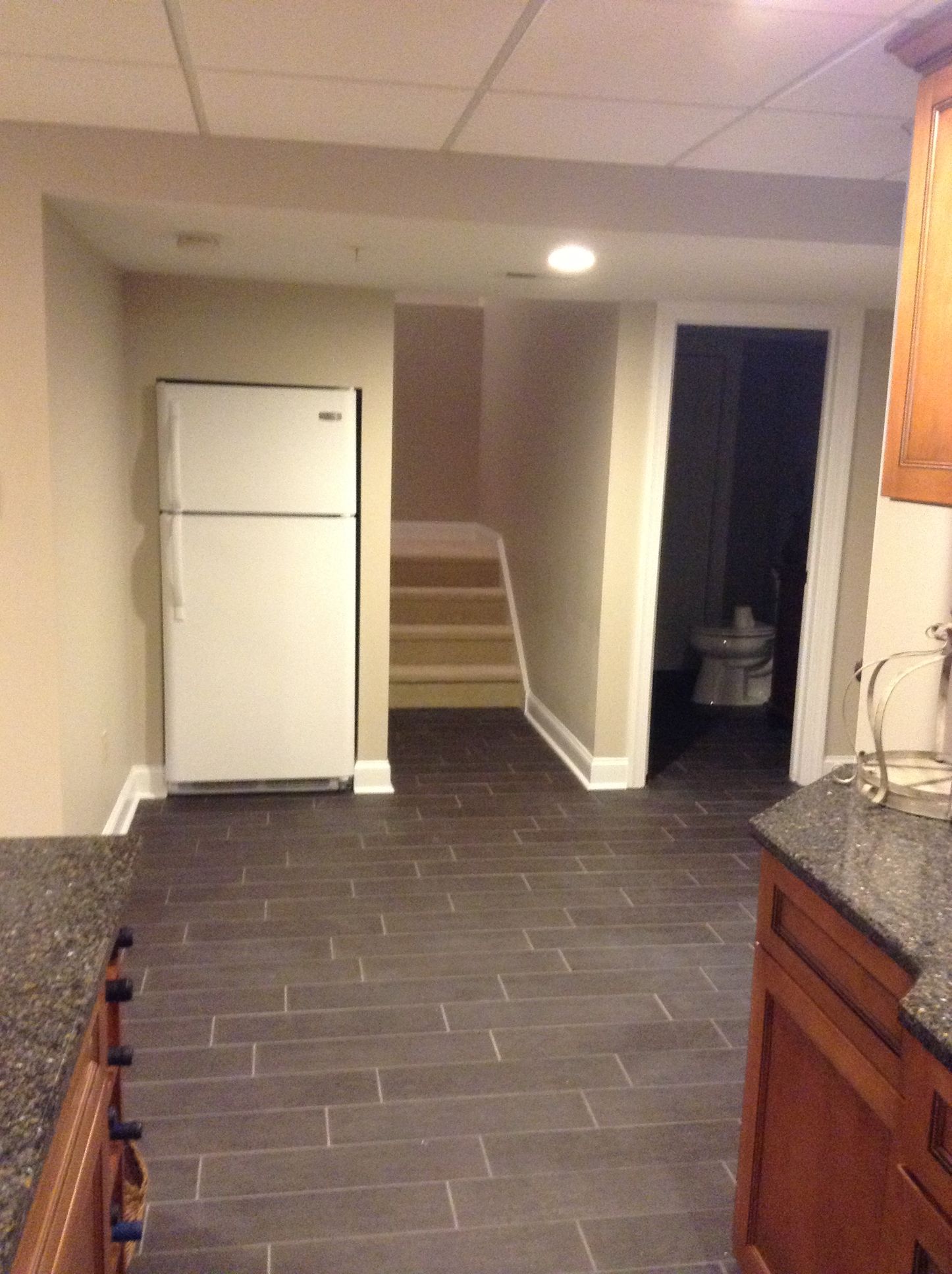 A kitchen with a refrigerator and stairs leading to a bathroom