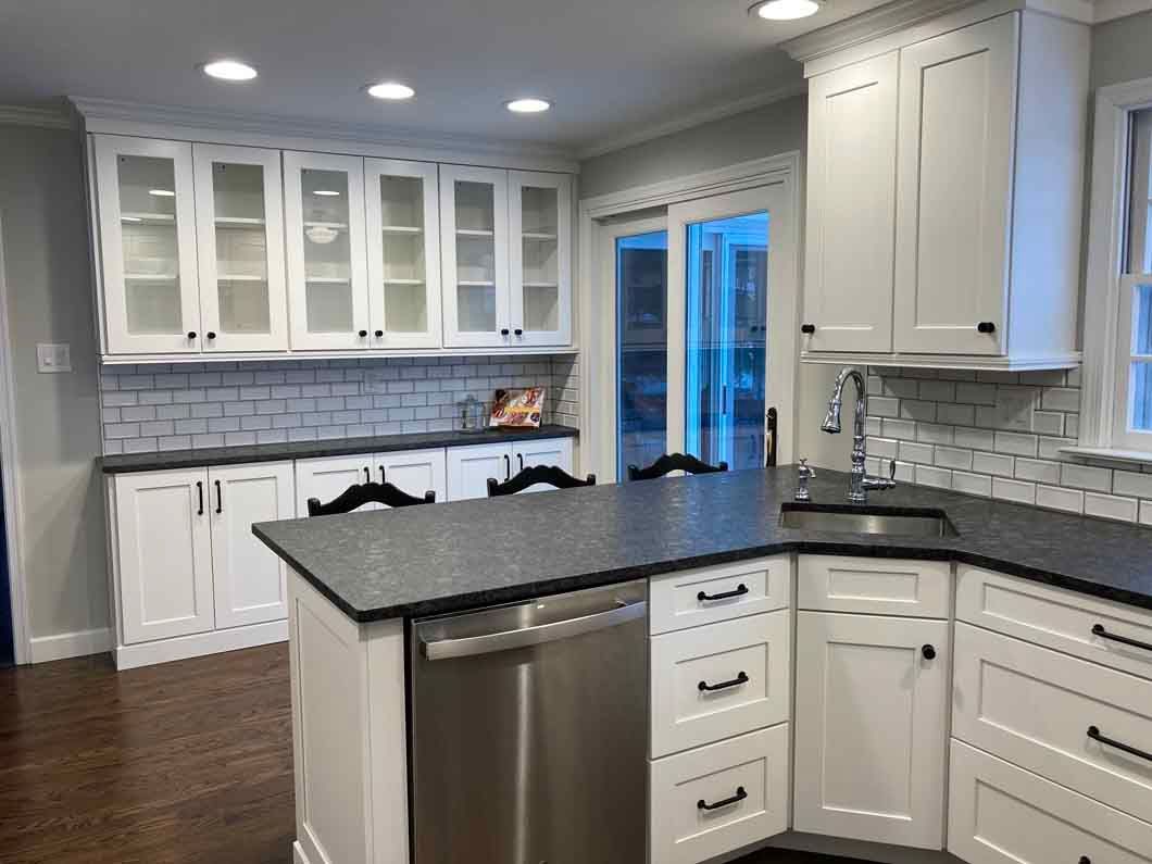 A kitchen with white cabinets , black counter tops , and stainless steel appliances.