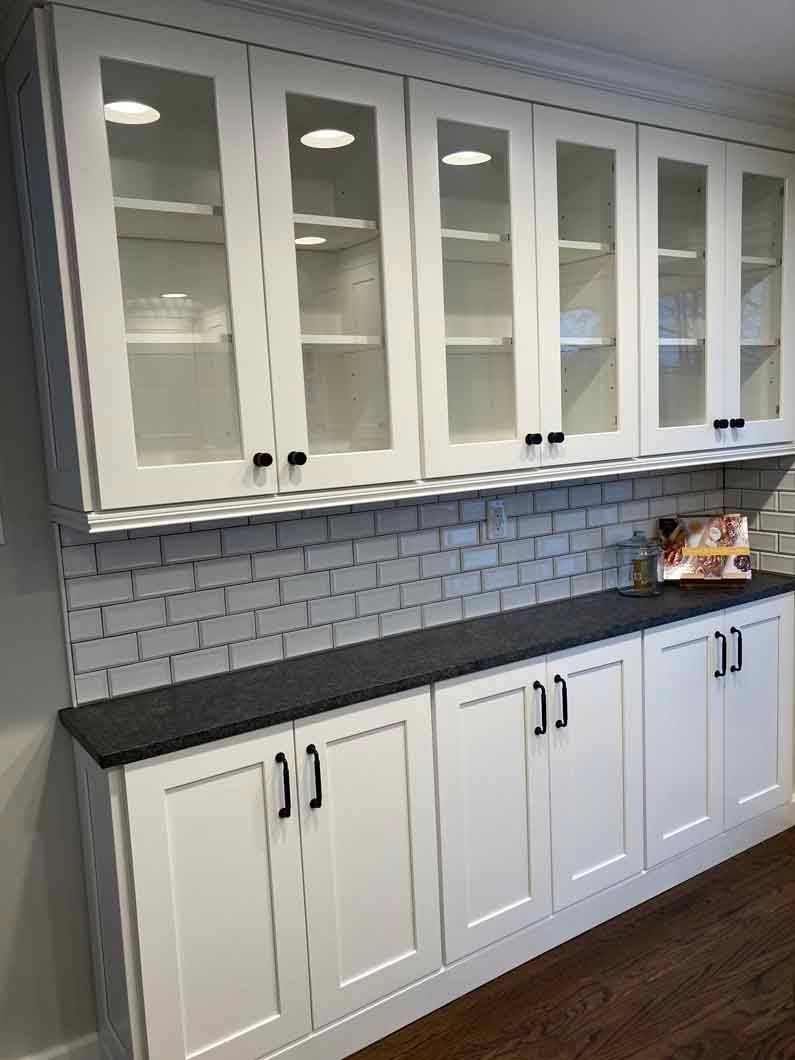 A kitchen with white cabinets and a black counter top.