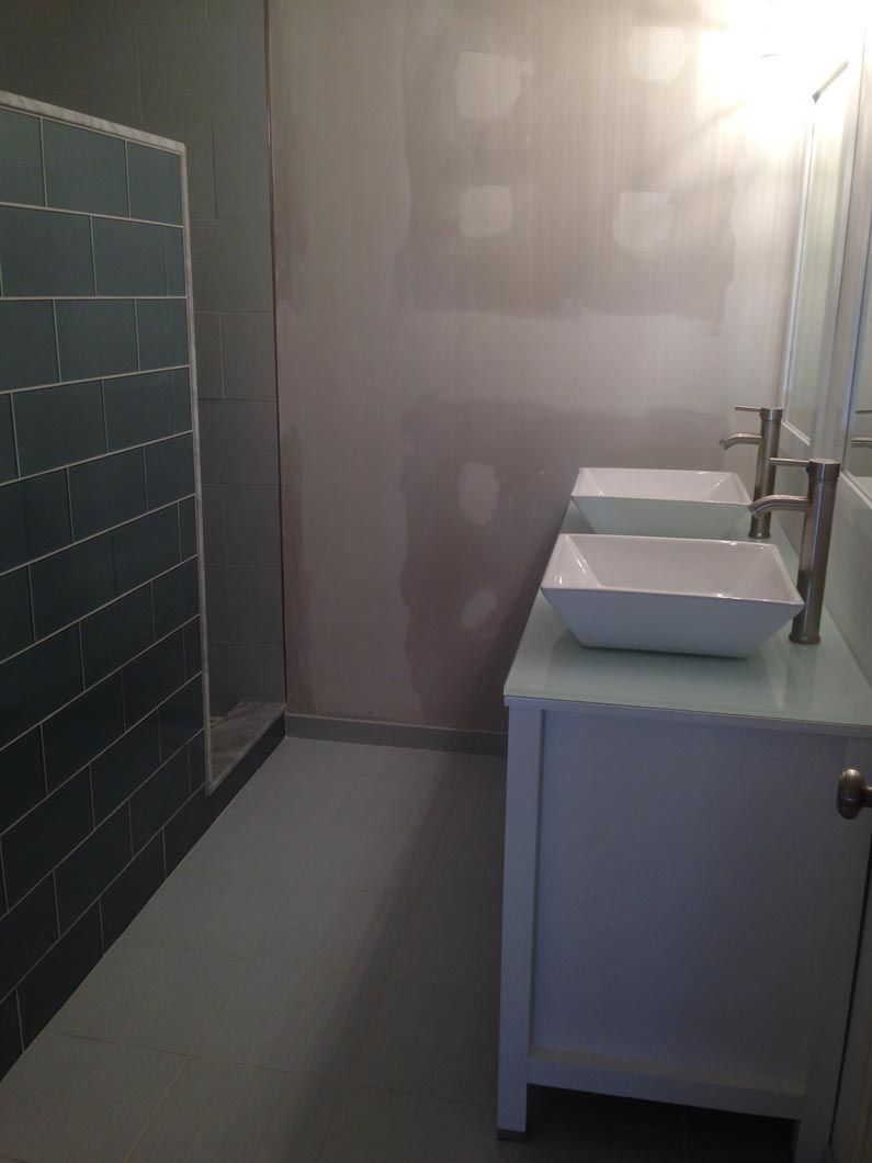 A bathroom with two sinks and a walk in shower.