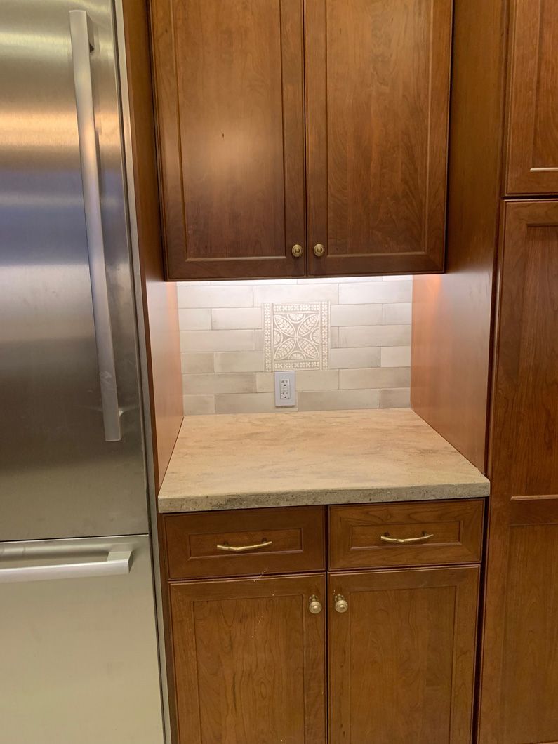 A kitchen with wooden cabinets and a stainless steel refrigerator.