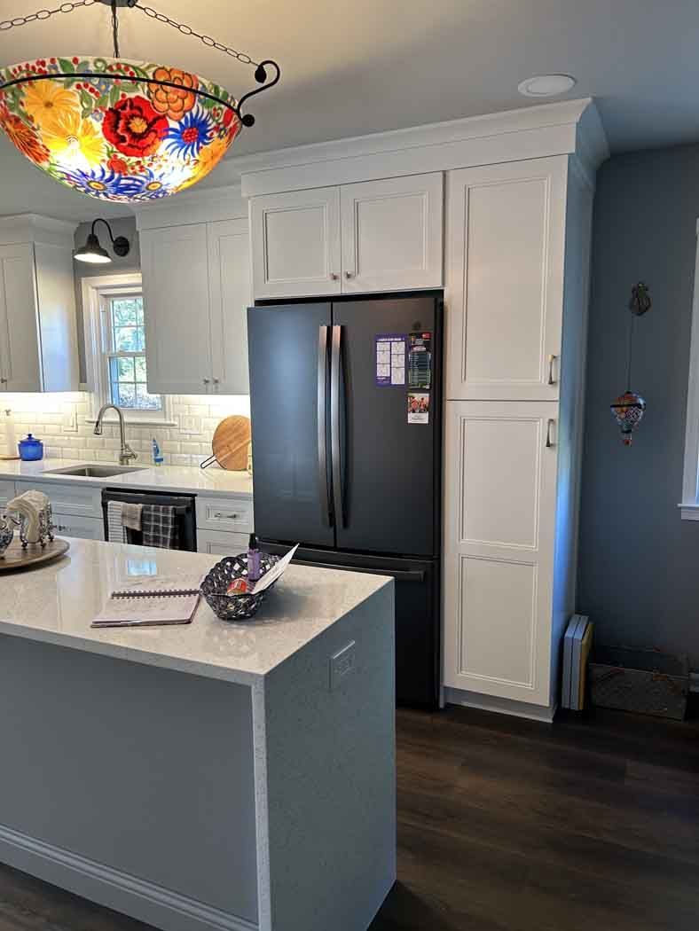 A kitchen with white cabinets and a black refrigerator.