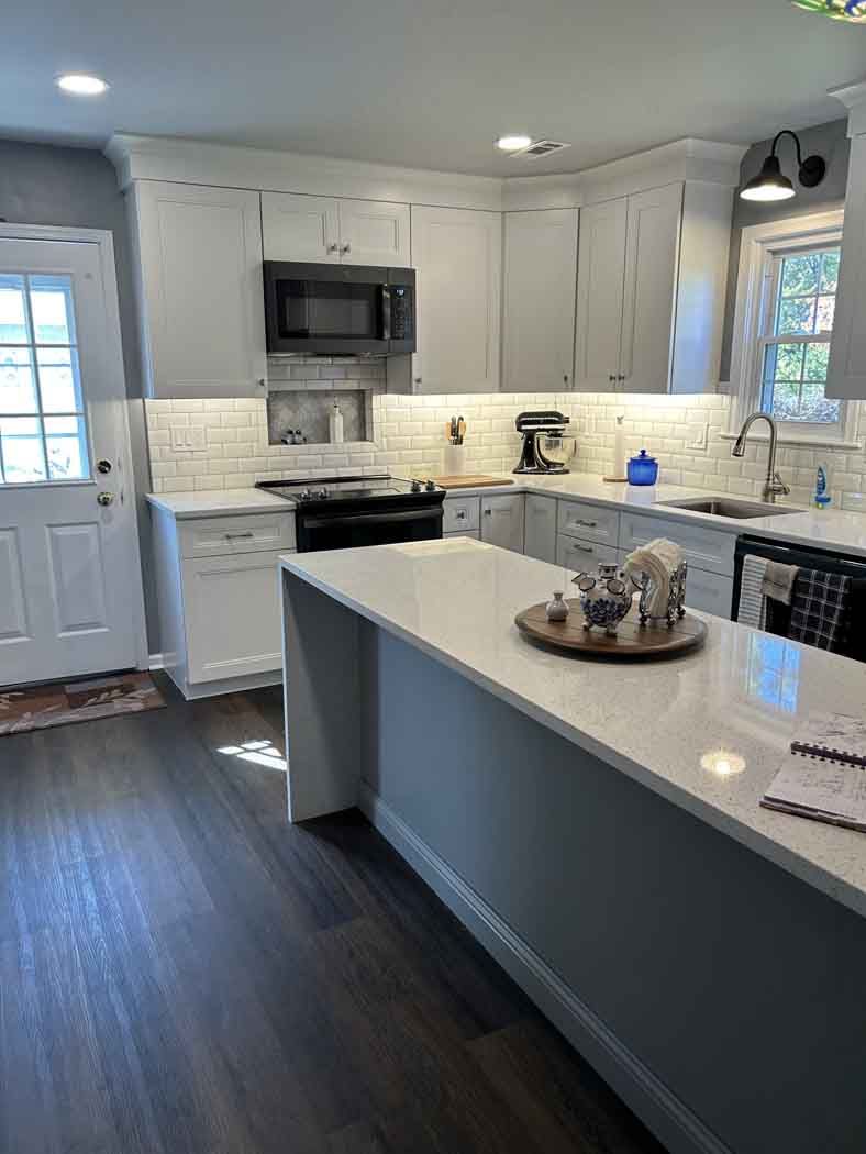 A kitchen with white cabinets , stainless steel appliances , and a large island.