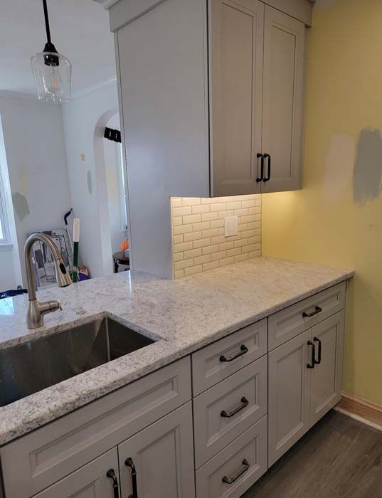 A kitchen with white cabinets , granite counter tops , and a sink.