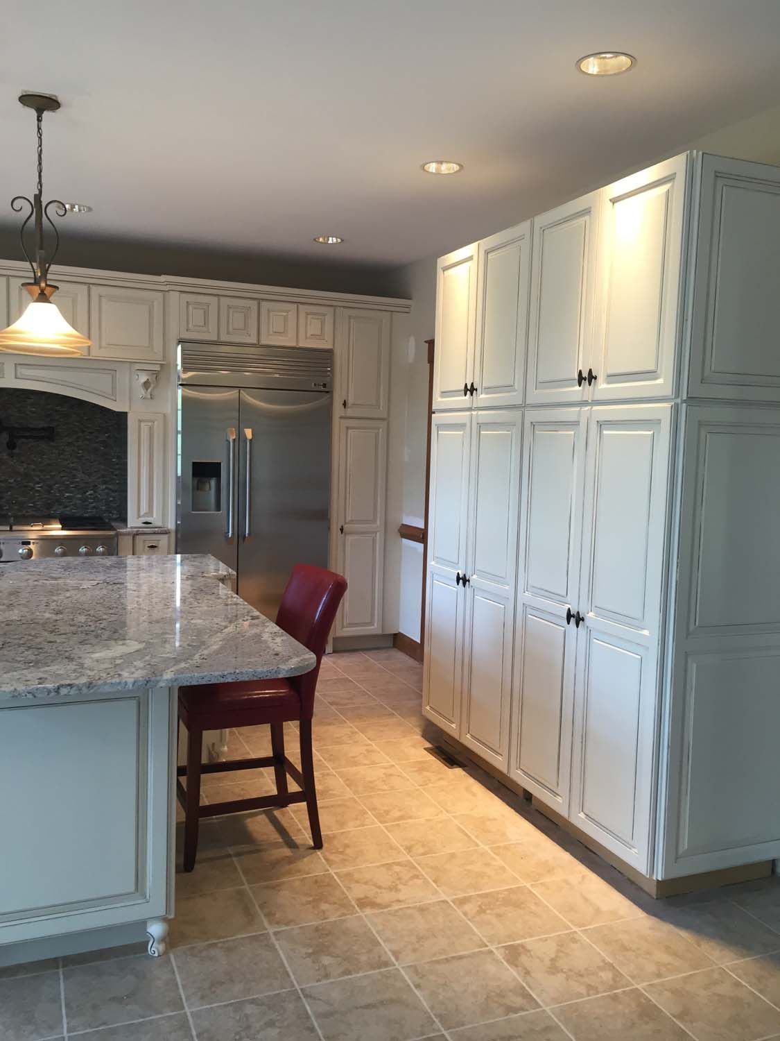 A kitchen with white cabinets , granite counter tops , and stainless steel appliances.