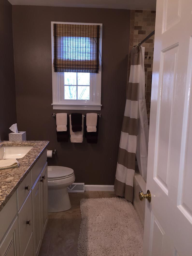 A bathroom with a toilet , sink , shower curtain and window.
