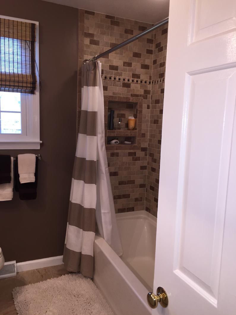 A bathroom with a striped shower curtain and a tub.