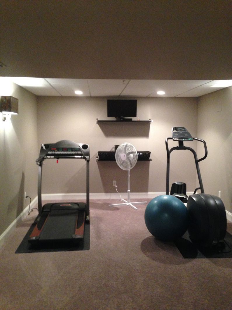 A gym with a treadmill a pilates ball and a fan