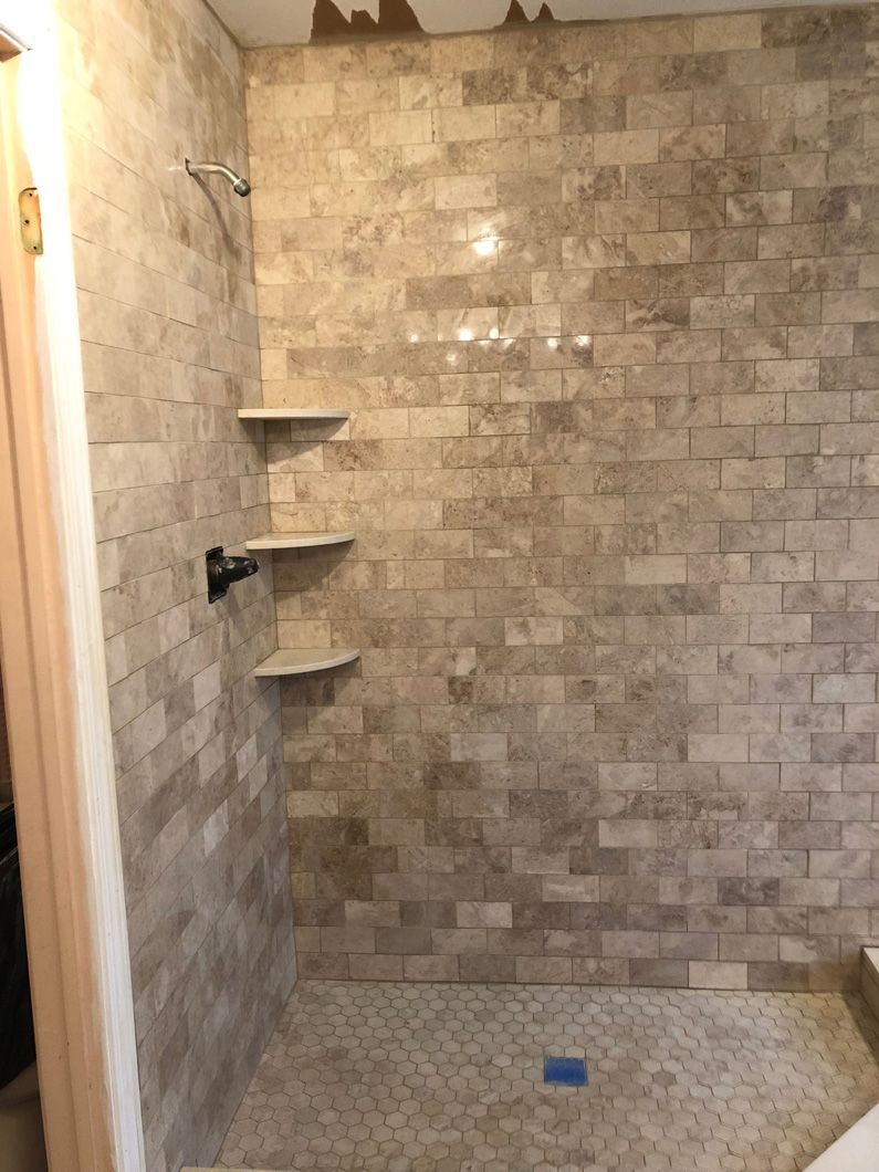 A bathroom with a walk in shower and a brick wall.